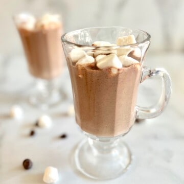 Two glass mugs filled with hot chocolate made from chocolate chips.