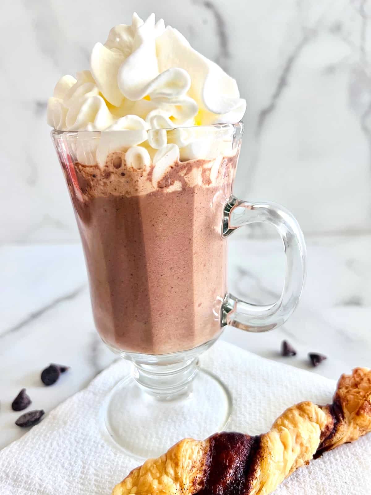 Best Hot Chocolate with Chocolate Chips in a glass topped wtih whipped cream and served wtih a cinnamon twist puff pastry.