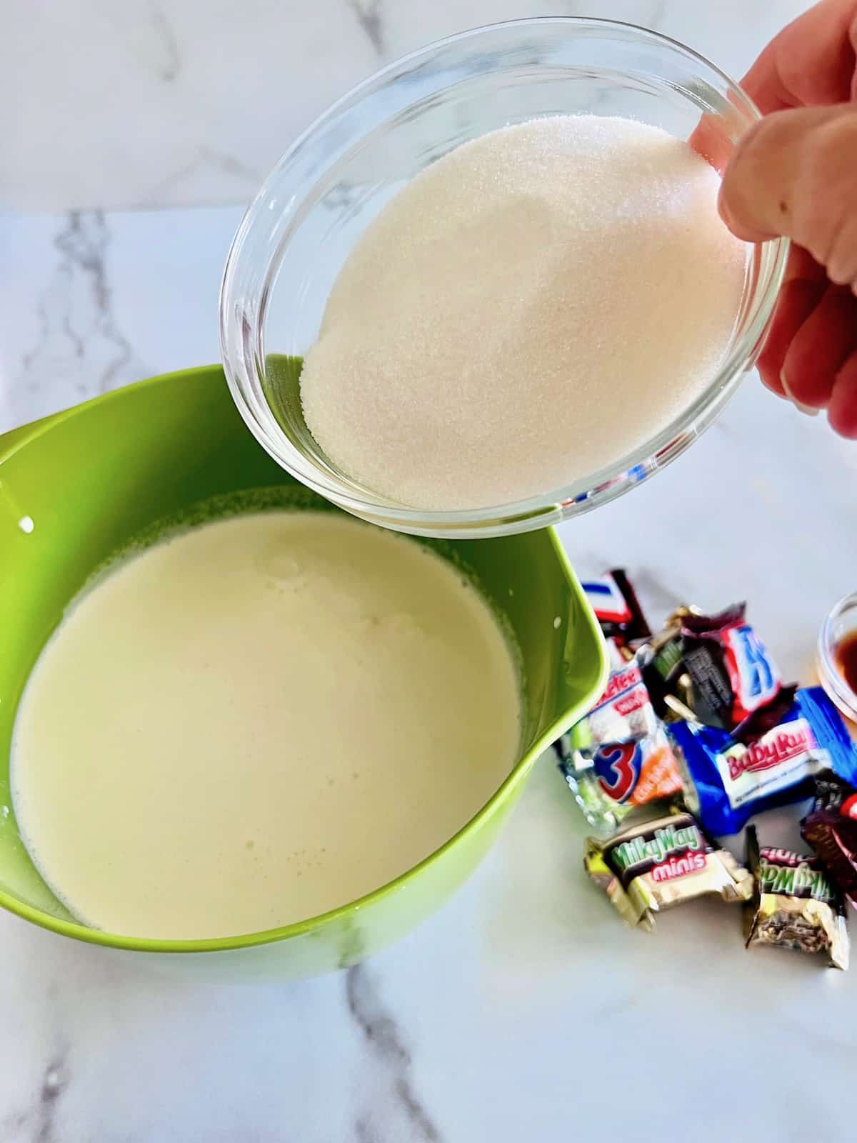 Adding sugar to the cream and milk in a mixing bowl.