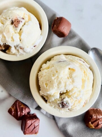 Two bowls with candy bar ice cream scoops.