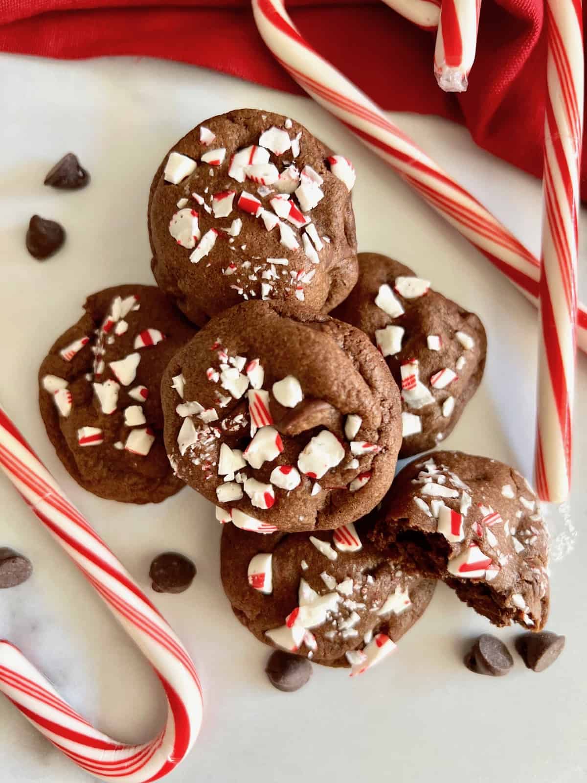 Peppermint Mocha Cookies Lined on a table topped with candy cane pieces and candy canes around them.