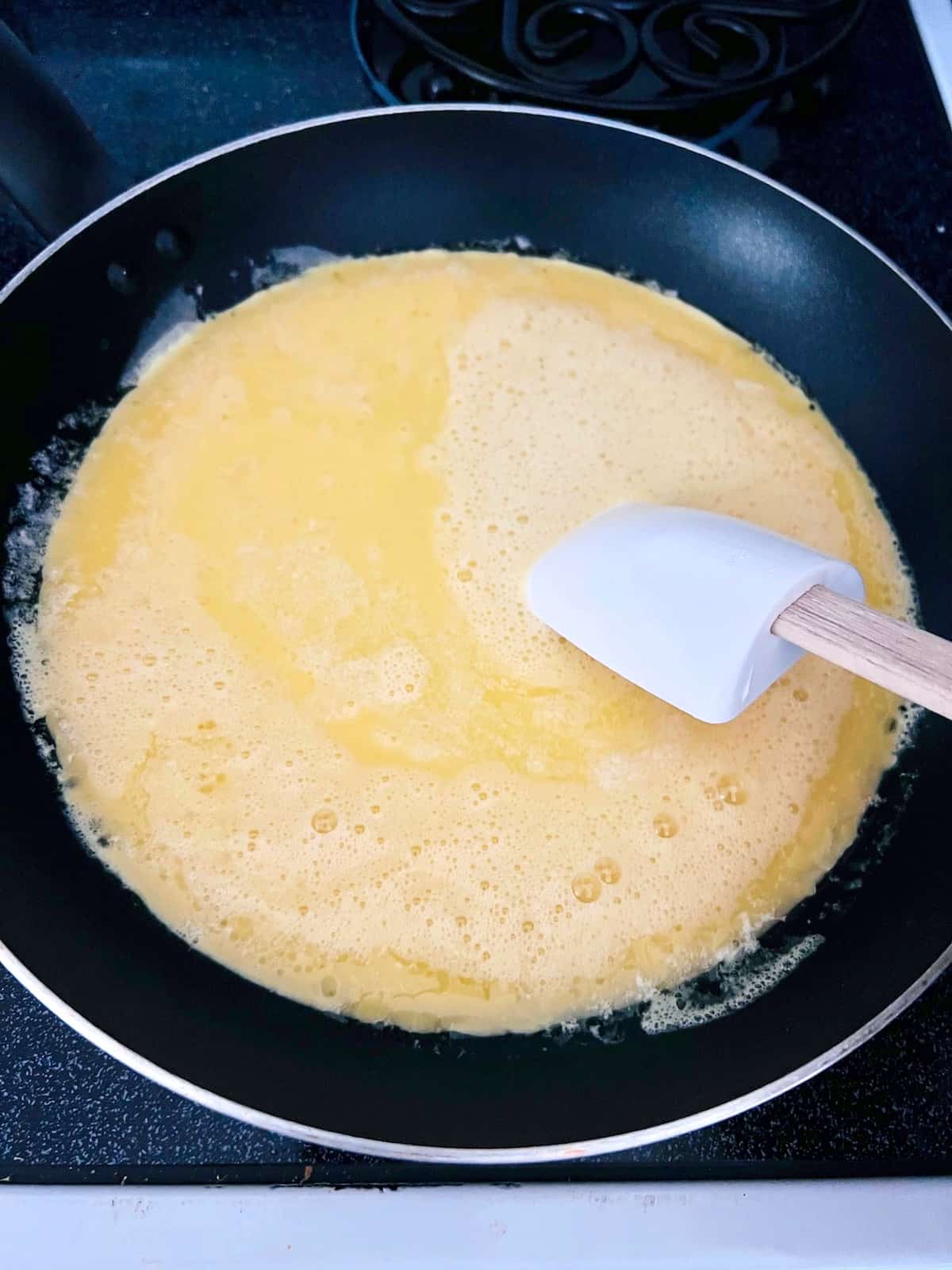 Raw eggs pouring into the skillet with melted butter.