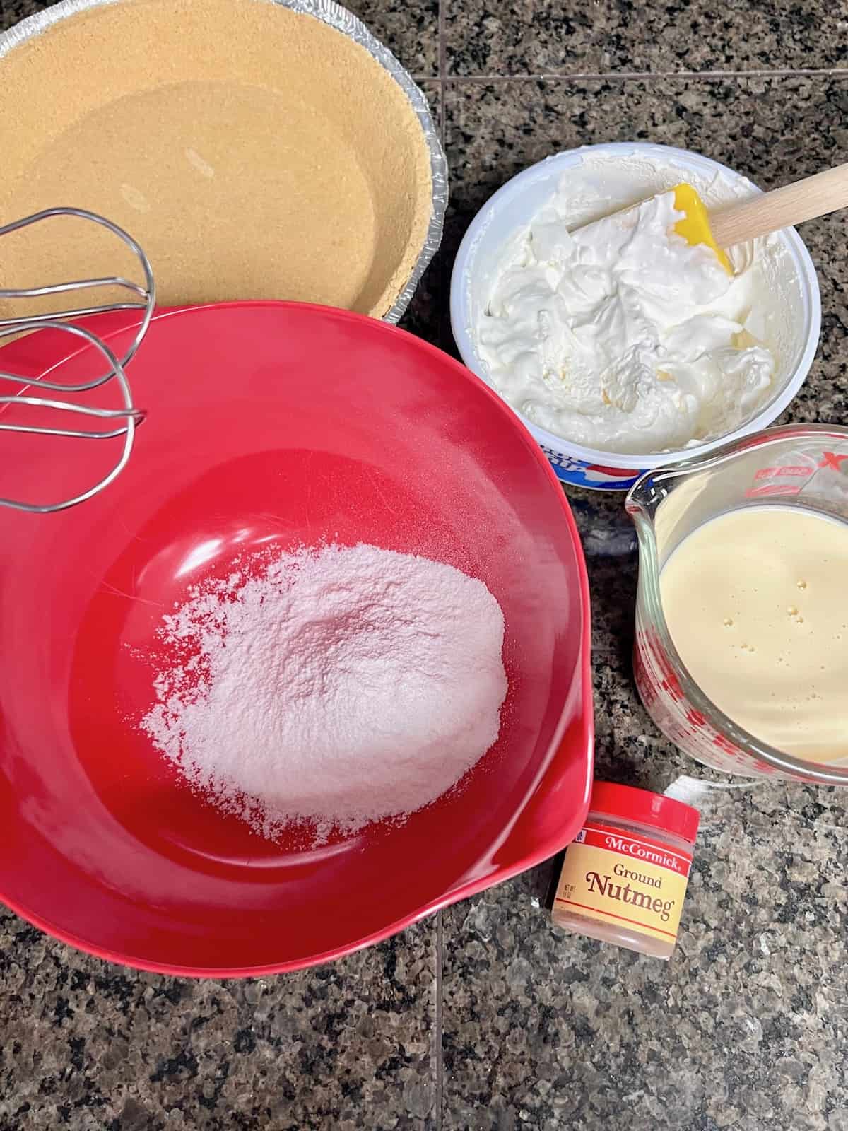 Mixing bowl with instant pudding and remaining ingredients on the counter.