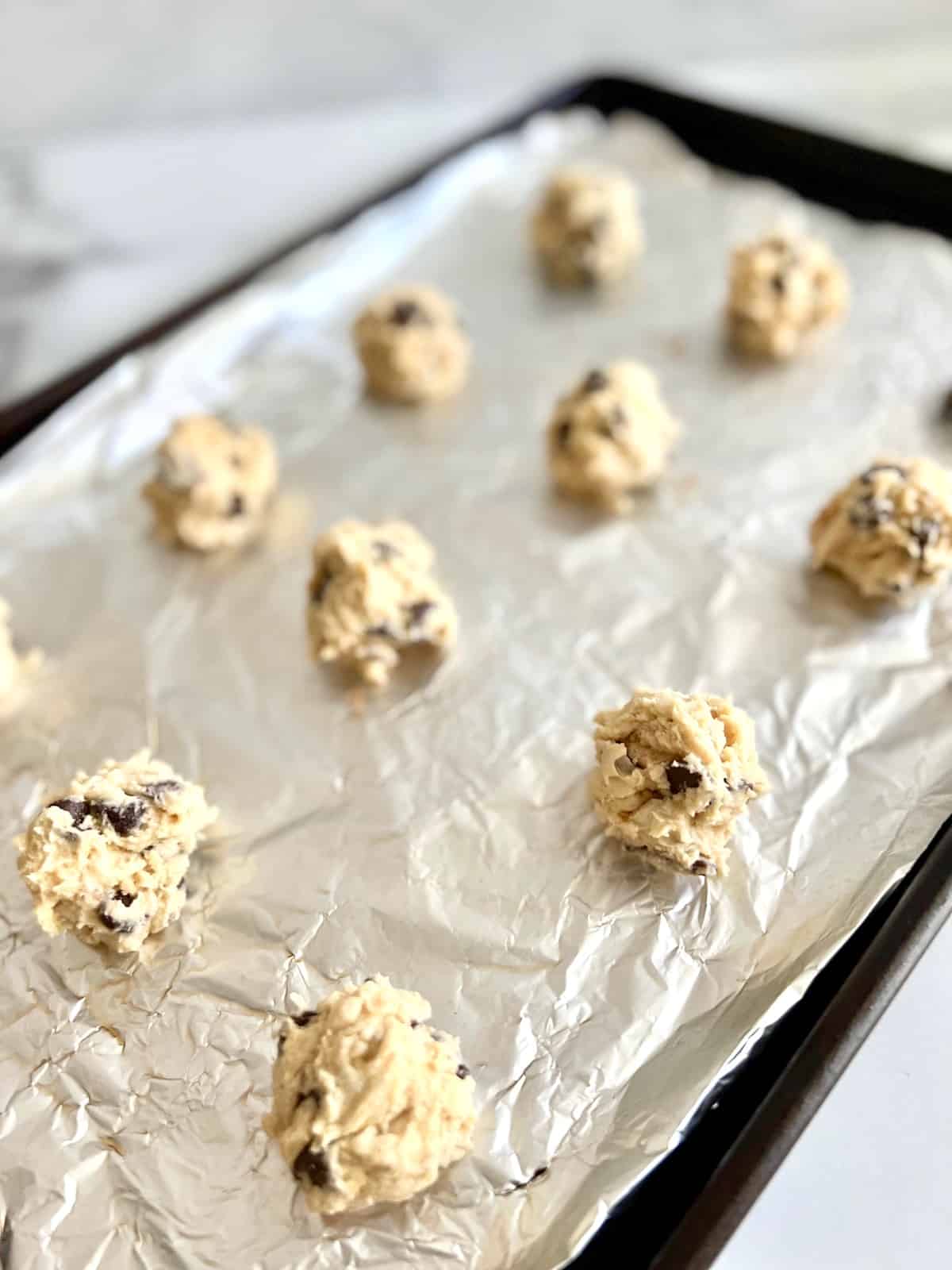 Sea Salt Toffee Chocolate Chip Cookies raw dough balls on a prepared baking sheet.