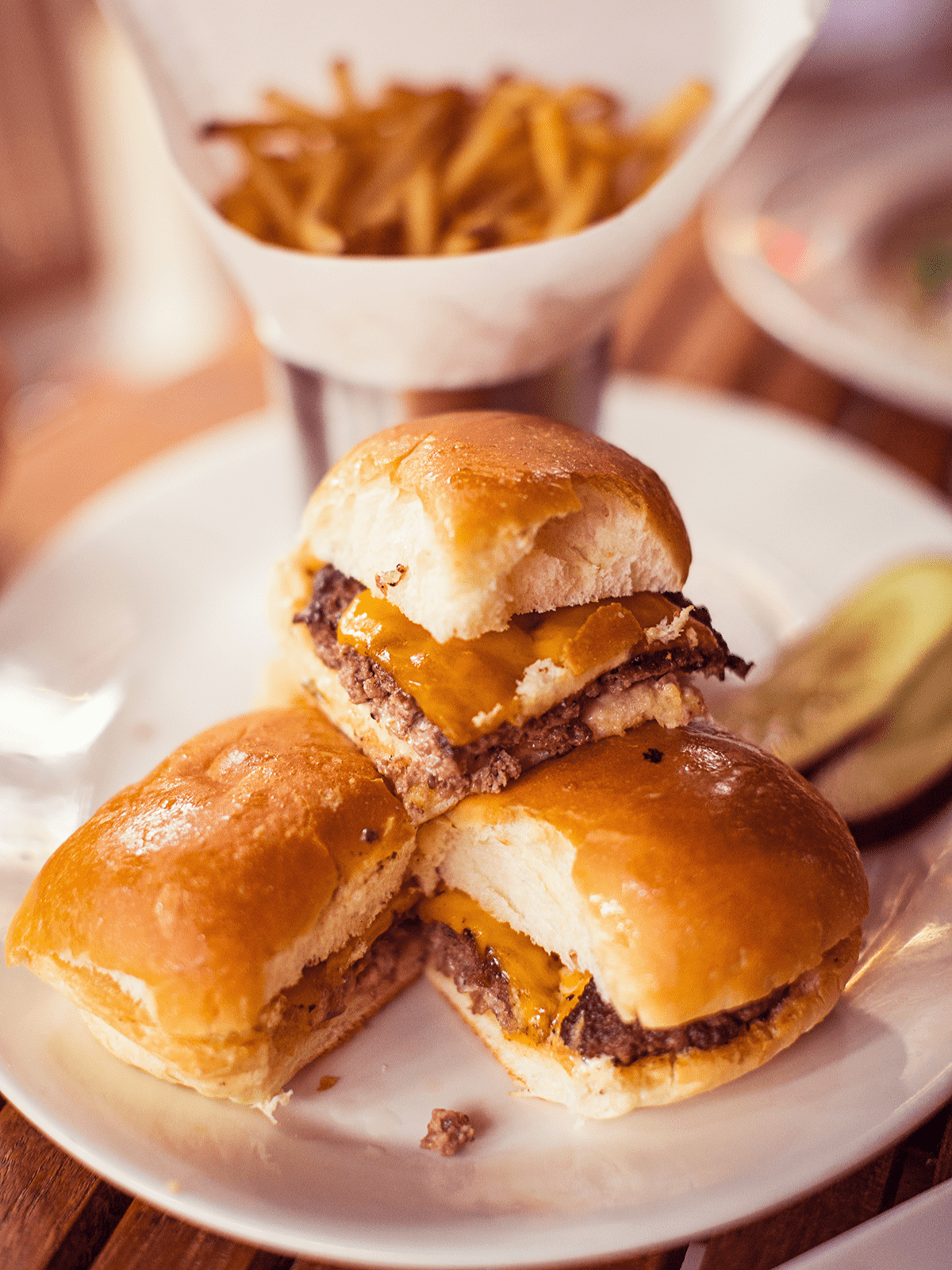 Cheeseburger sliders plated and served with fries.