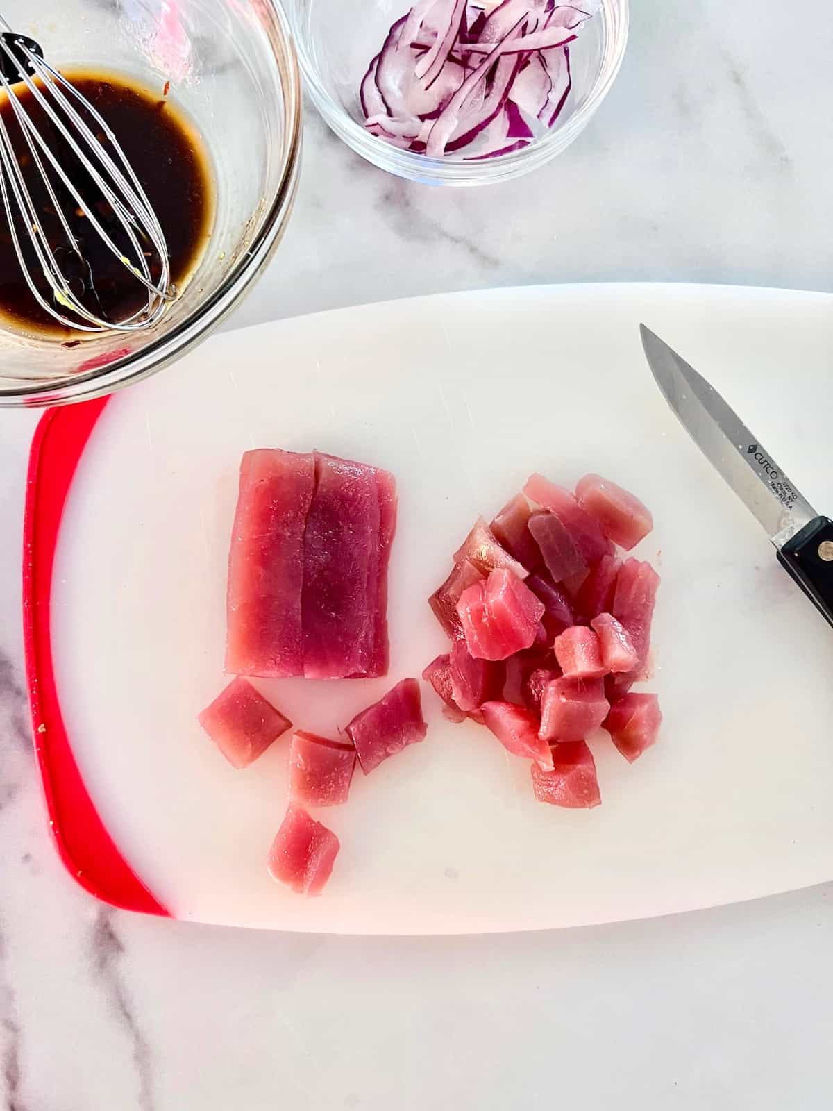 Fresh ahi tuna cut into small cubes on a cutting board.