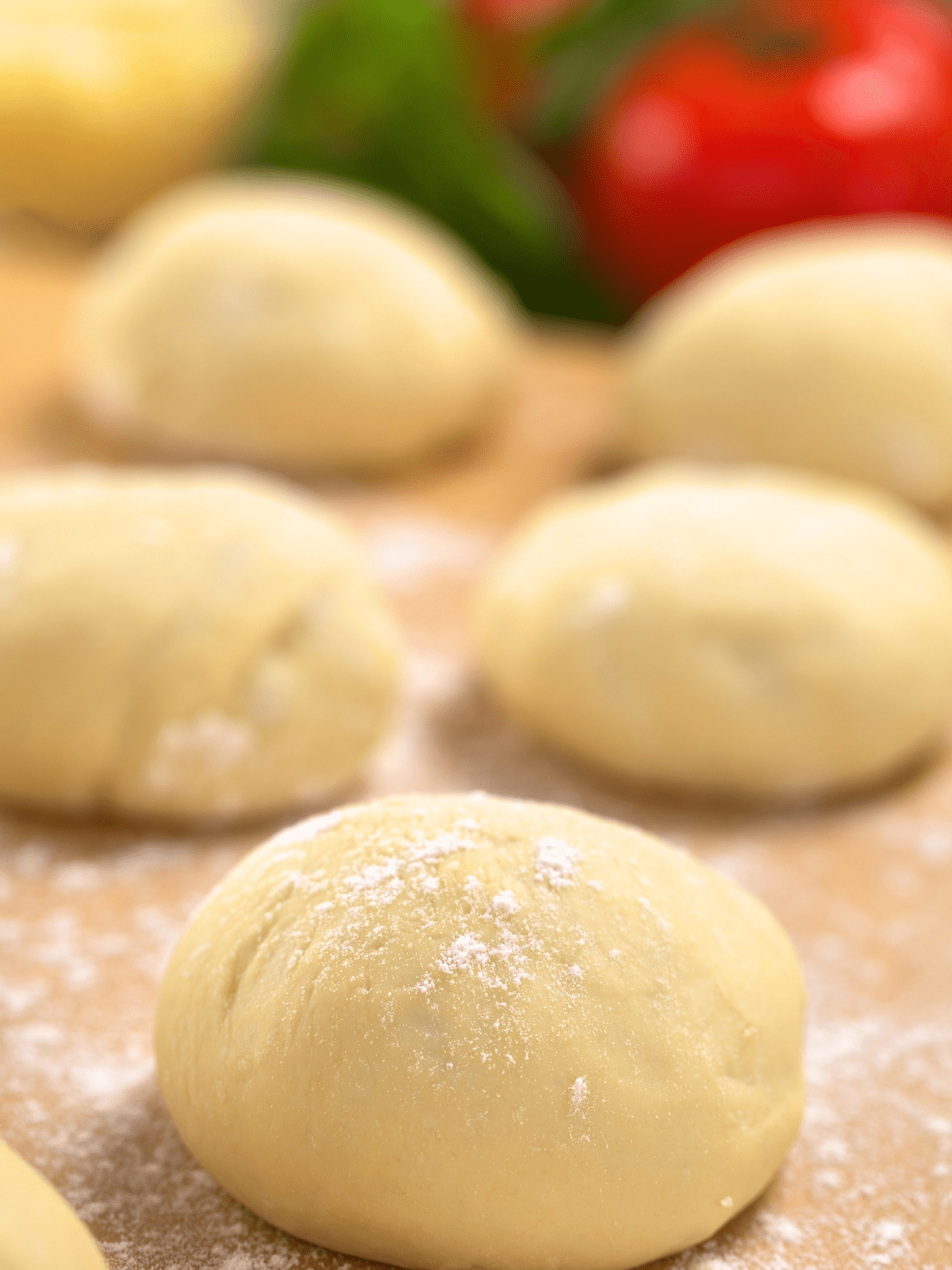 Balls of pizza dough on a floured board.