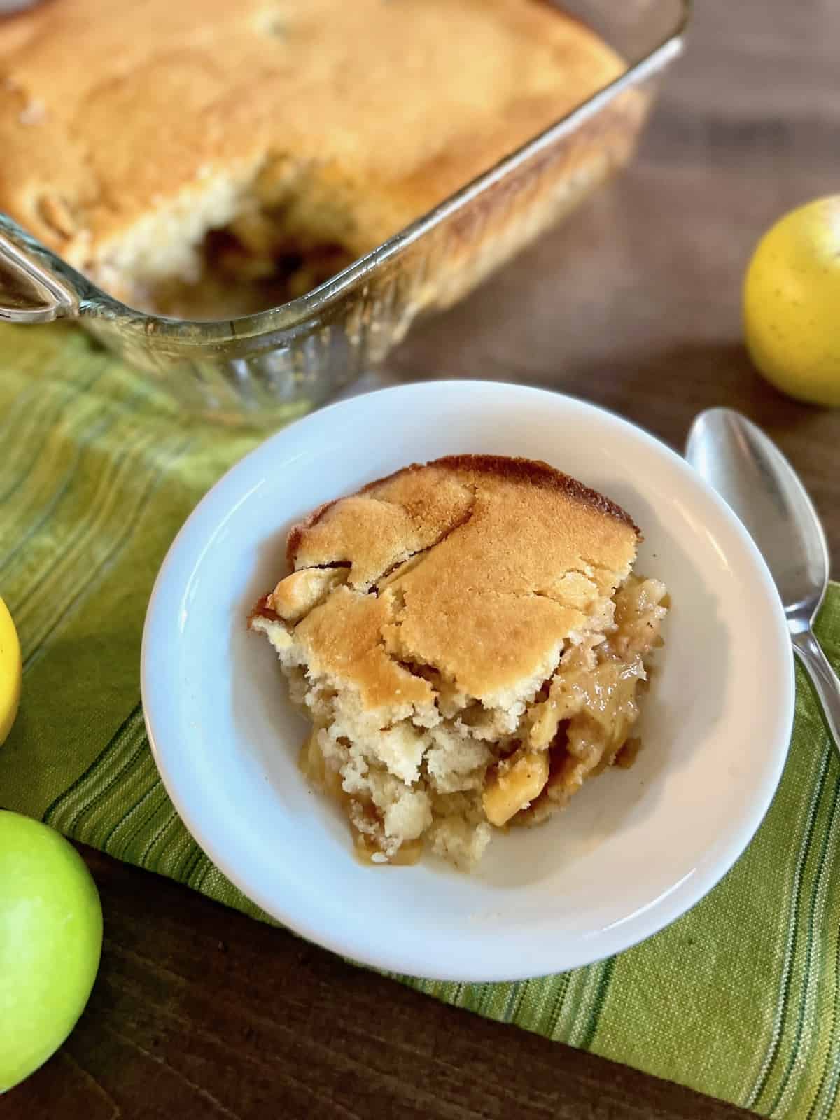 Gluten-Free Apple Cobbler Bowl with a slice and full baking dish in the back ground