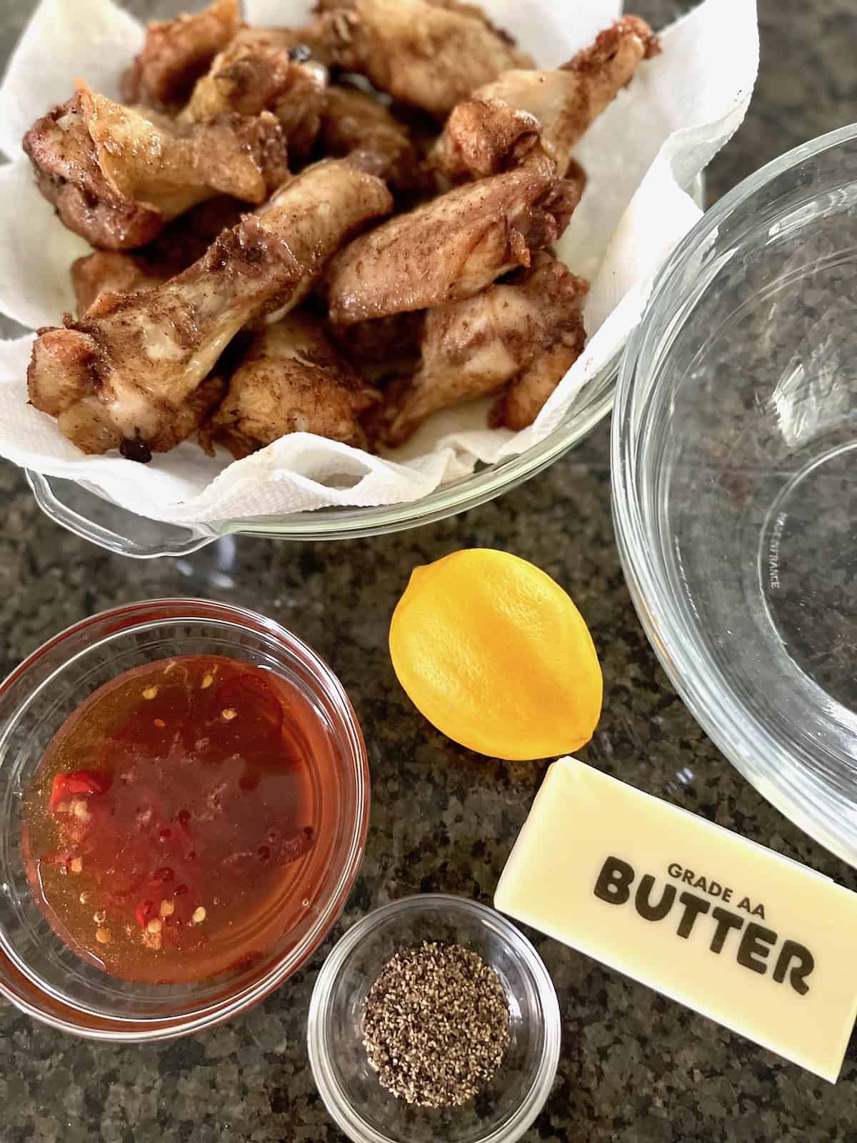 Hot Honey Lemon Pepper Wings Fried wings on paper towels with sauce ingredients on a table.