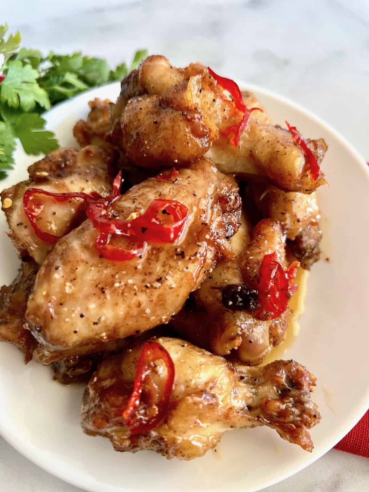 Hot Honey Lemon Pepper Wings Plated with sauce and hot peppers on top.