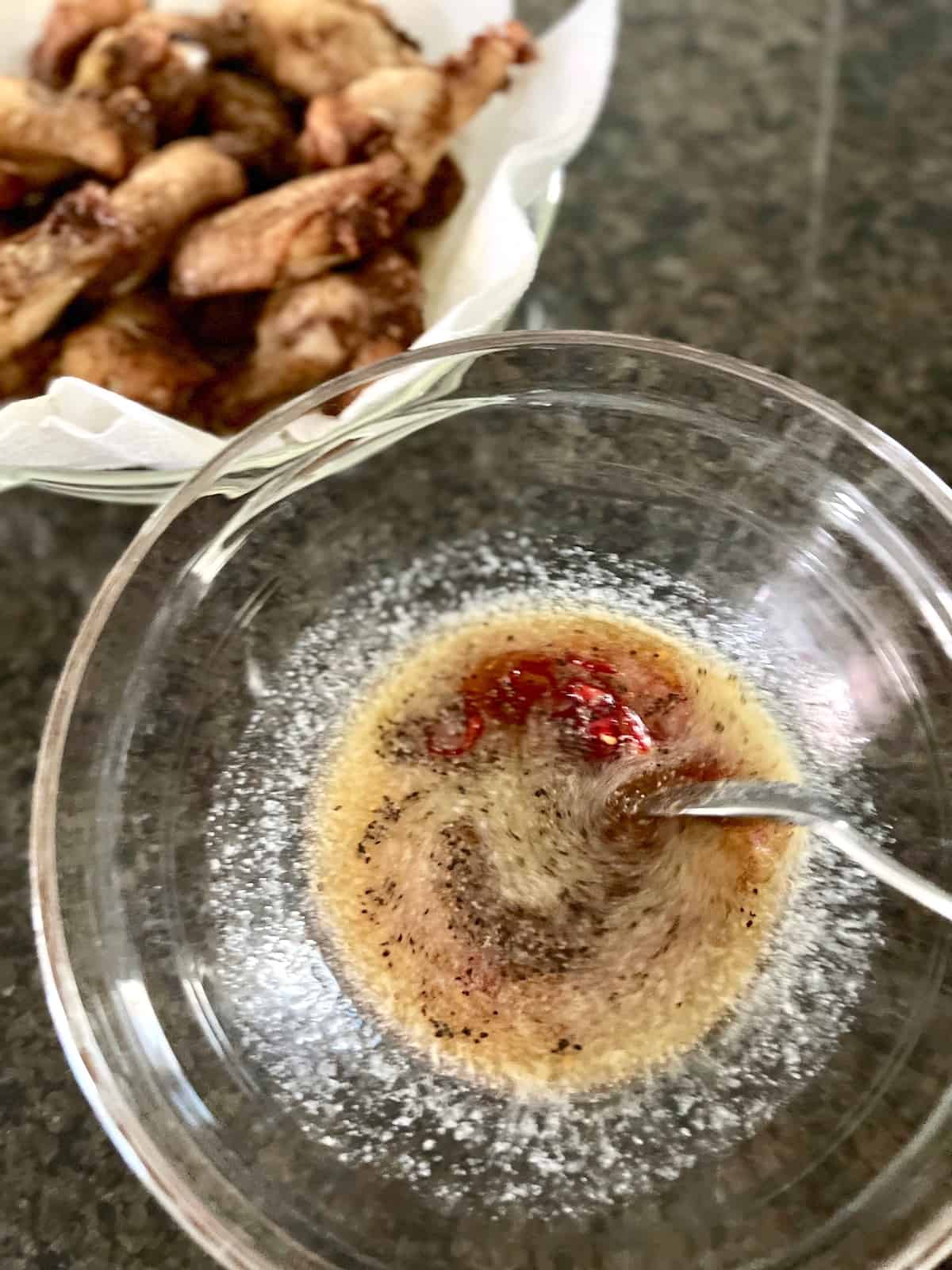 Hot Honey Lemon Pepper Wings Stirring sauce ingredients in a large bowl.