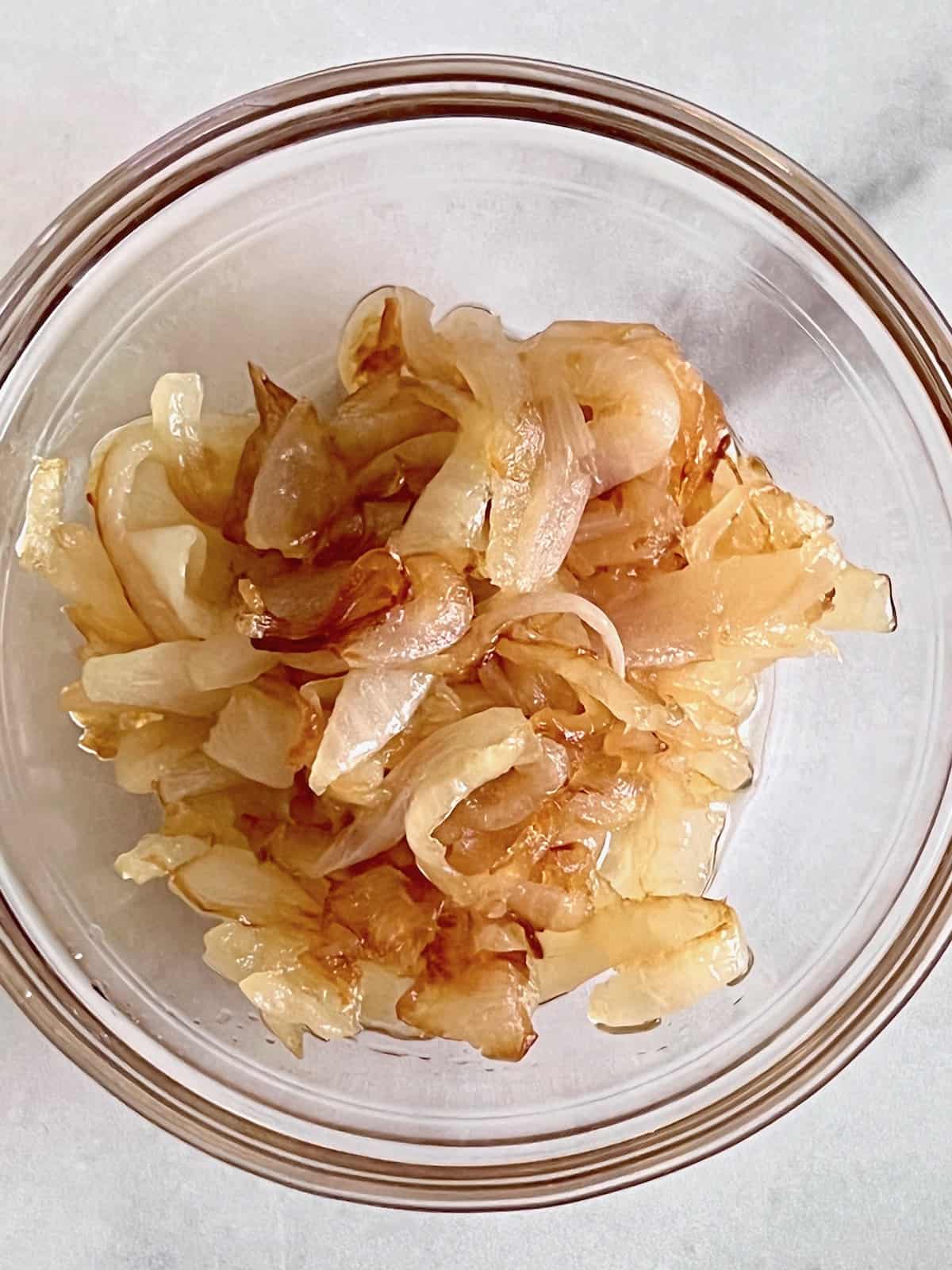 How to Caramelize OnionsÂ Lightly golden brown cooked in a glass bowl.