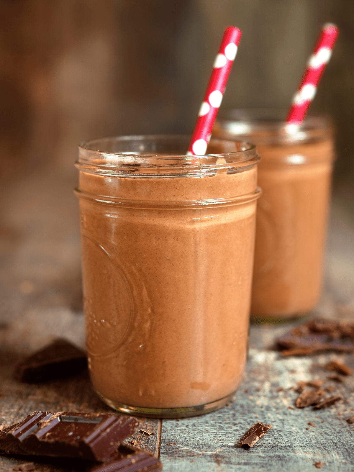 Chocolate smoothie in 2 glass cups with straws.