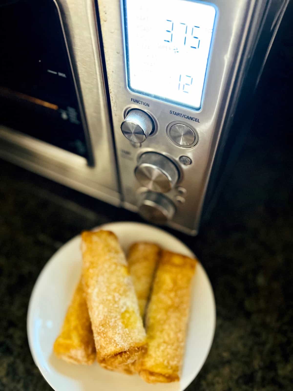 Frozen Egg Rolls on a plate in front of air fryer