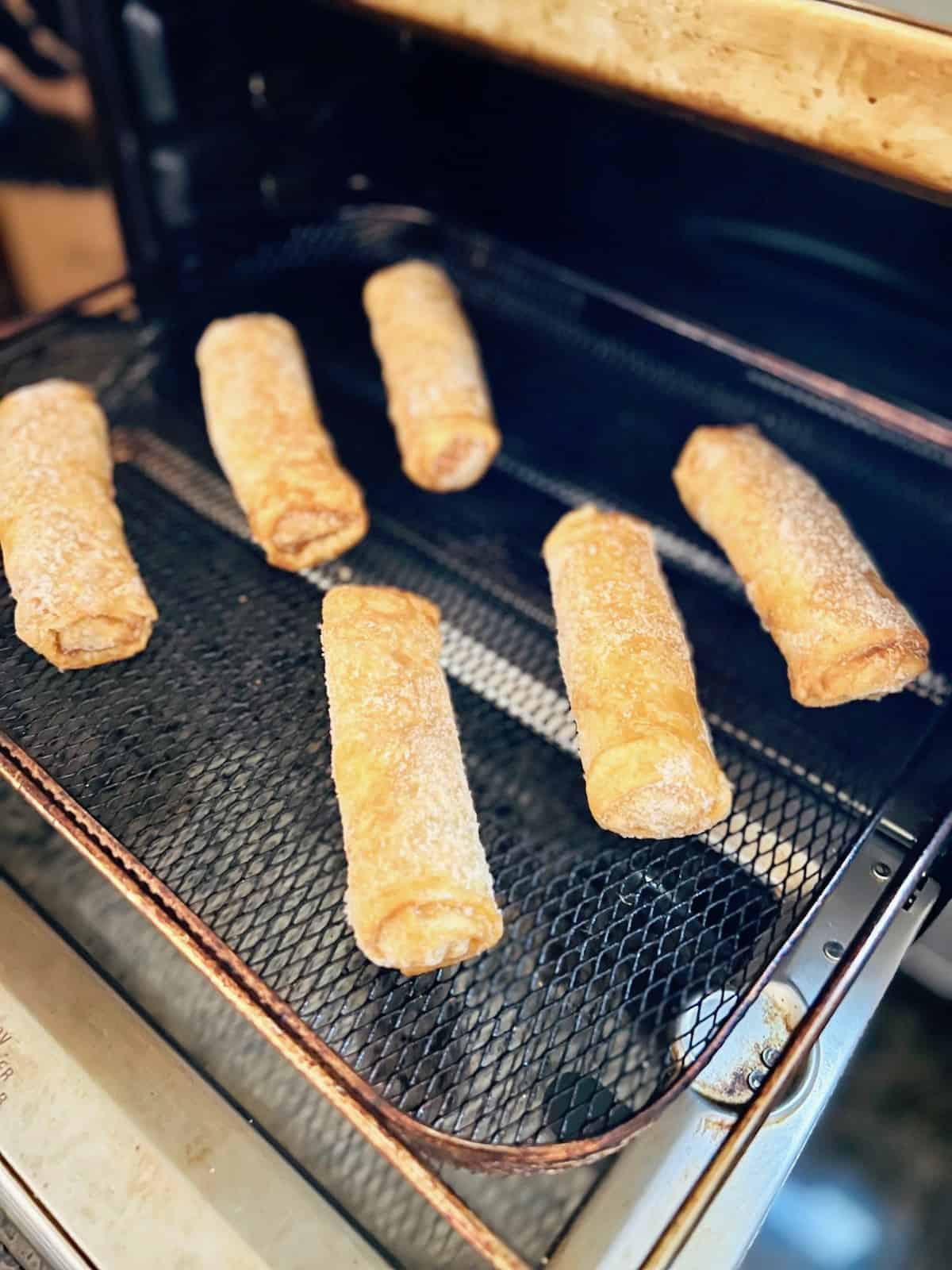 Frozen Egg Rolls on the air fryer tray.