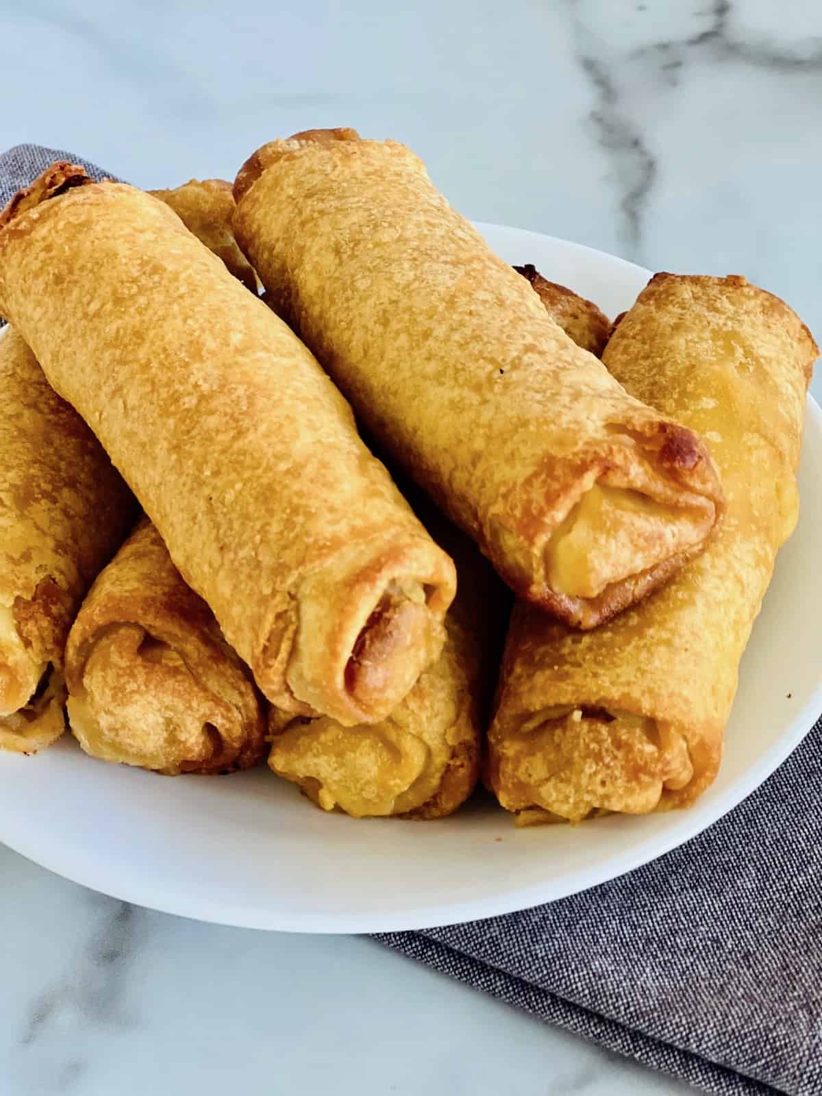 Egg Rolls Hot from the air fryer and stacked on a plate.