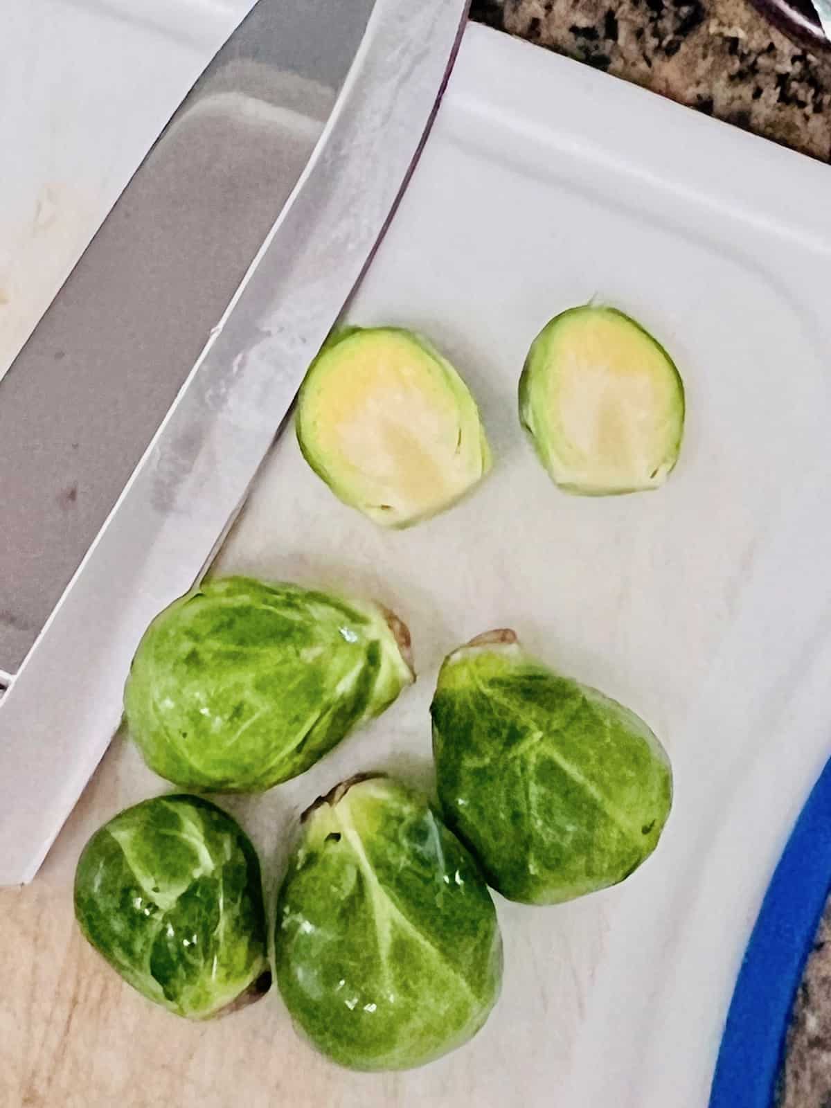 Asian-Inspired Teriyaki Brussels Sprouts Cut in half on a cutting board with knife.