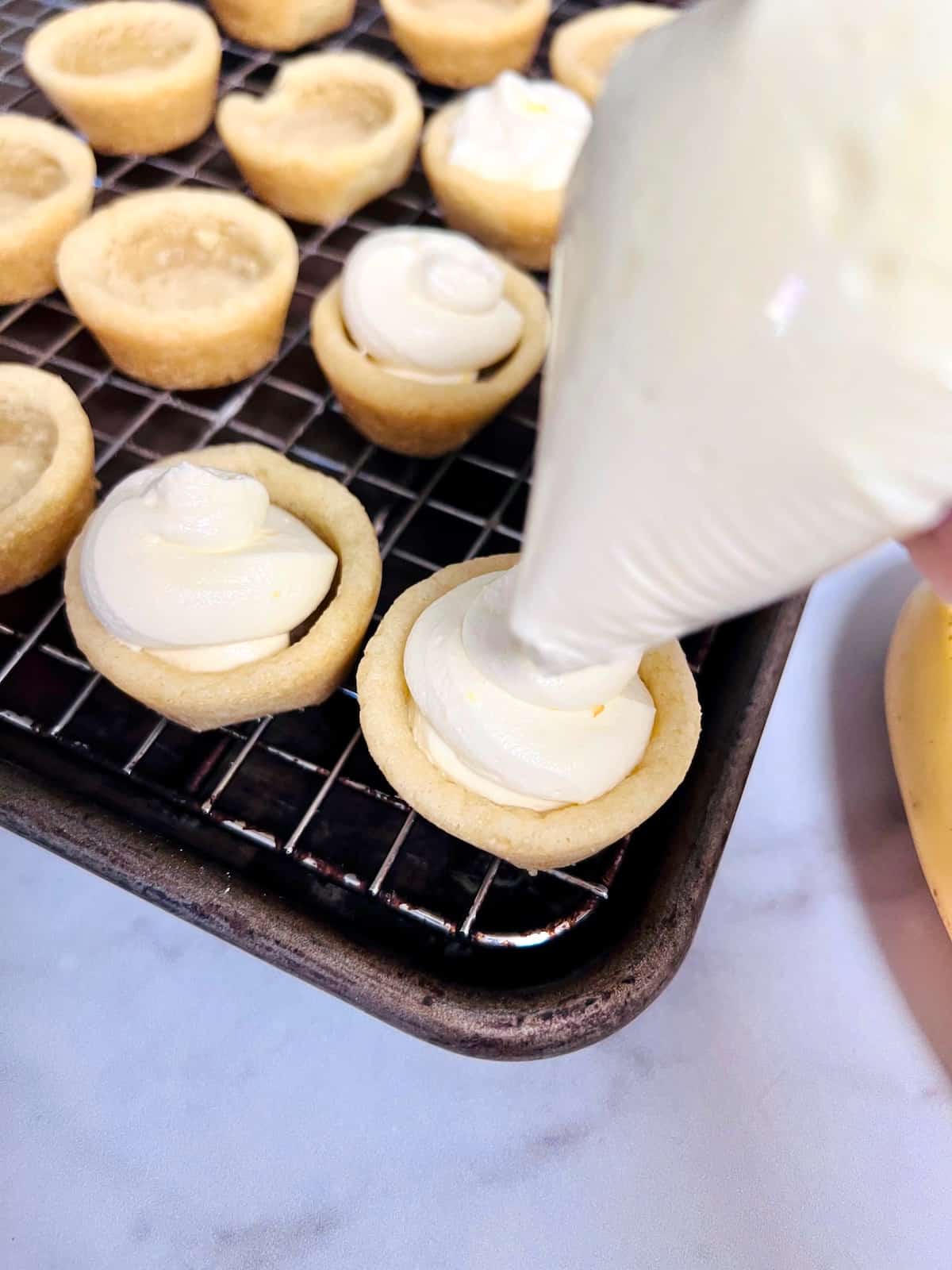 Banana Cream Pie Cookie Cups Squirting banana pudding cream filling into precooked cookie cups.