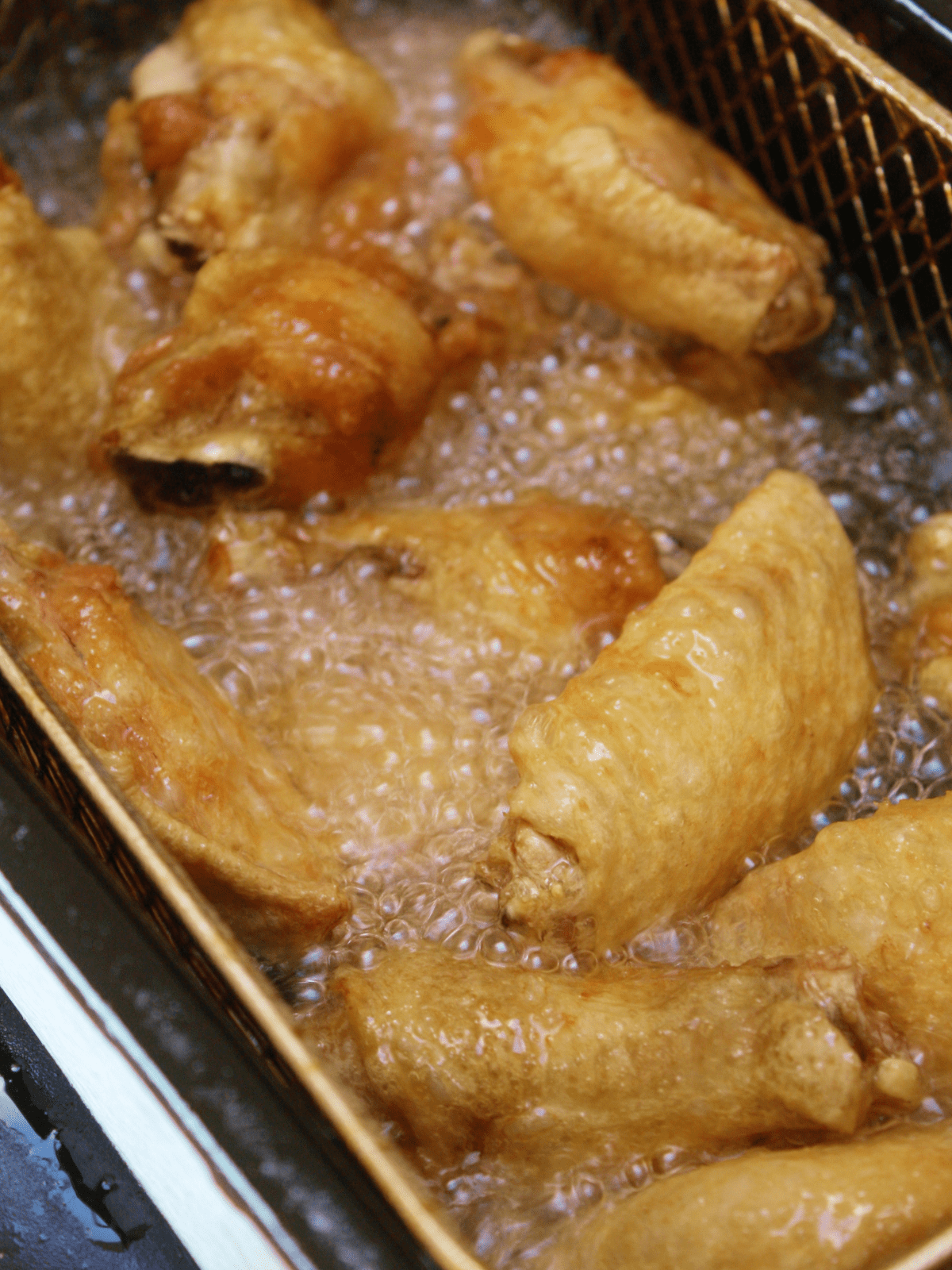 Wings in the deep fryer cooking in oil.
