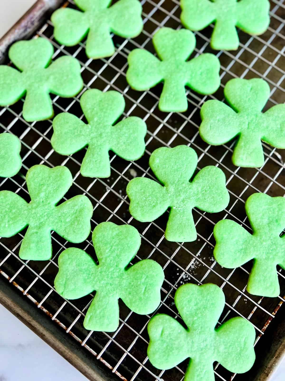 Green Shamrock Sugar Cookies Cooling on a rack.