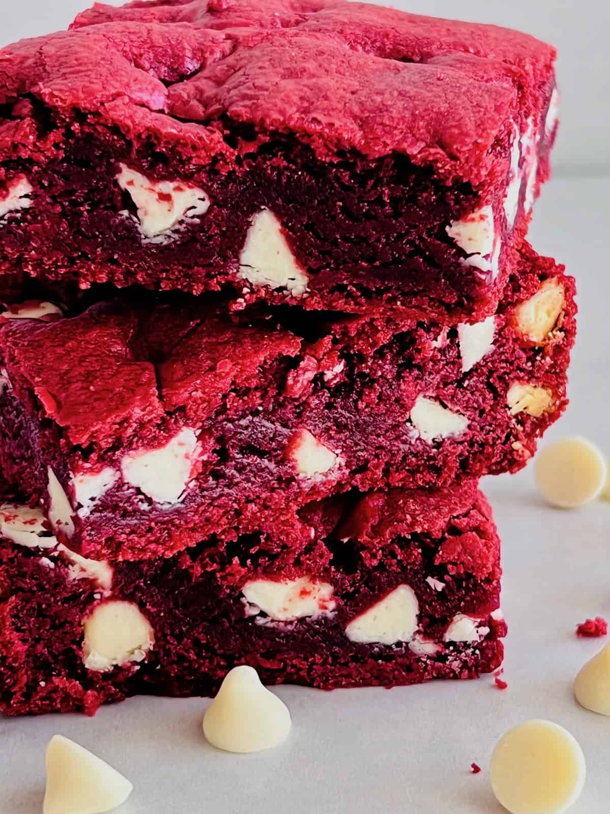 Red Velvet Brownies with Cake Mix 3 stacked closeup surrounded by white chocolate chips.