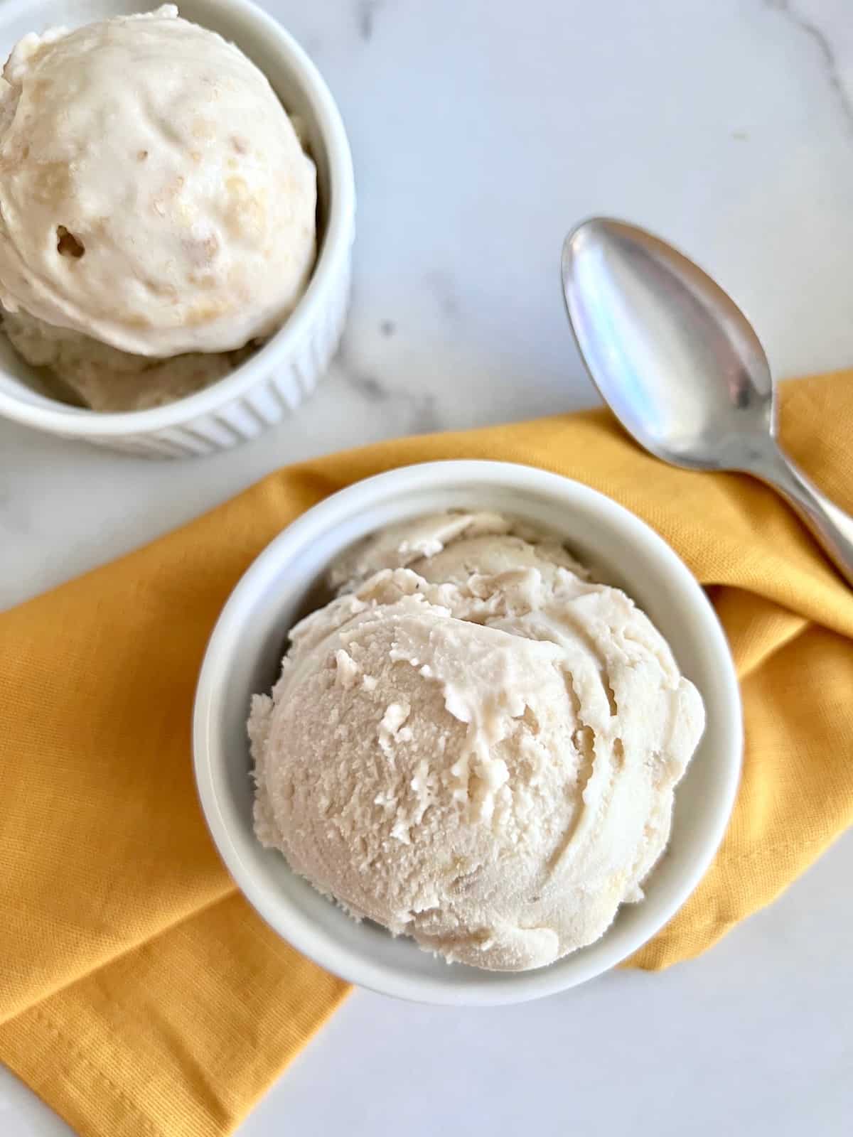 Banana Ice Cream Overhead two bowls with scoops and linen napkin and spoon.