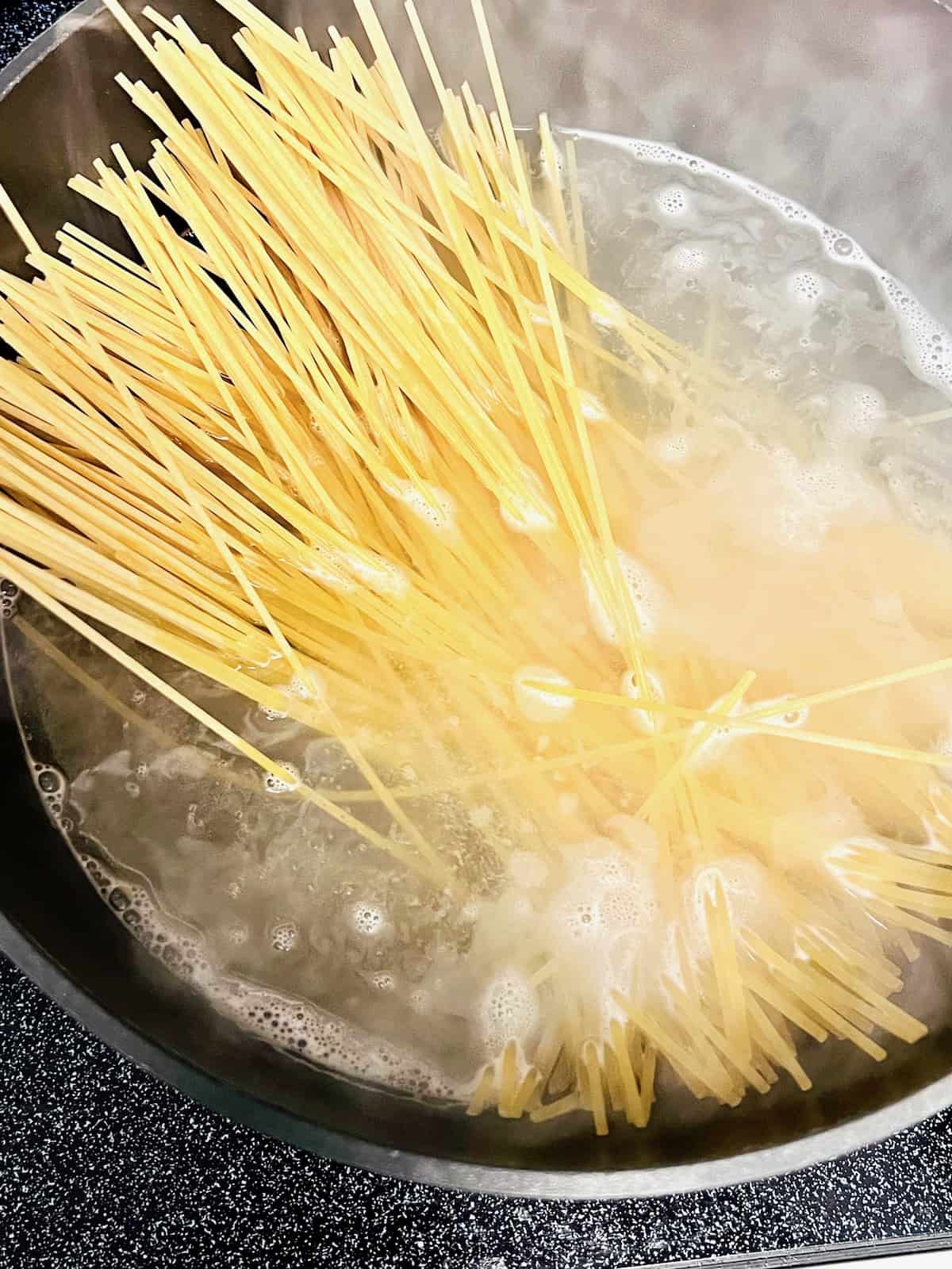 Spaghetti noodles in a pot of boiling water.