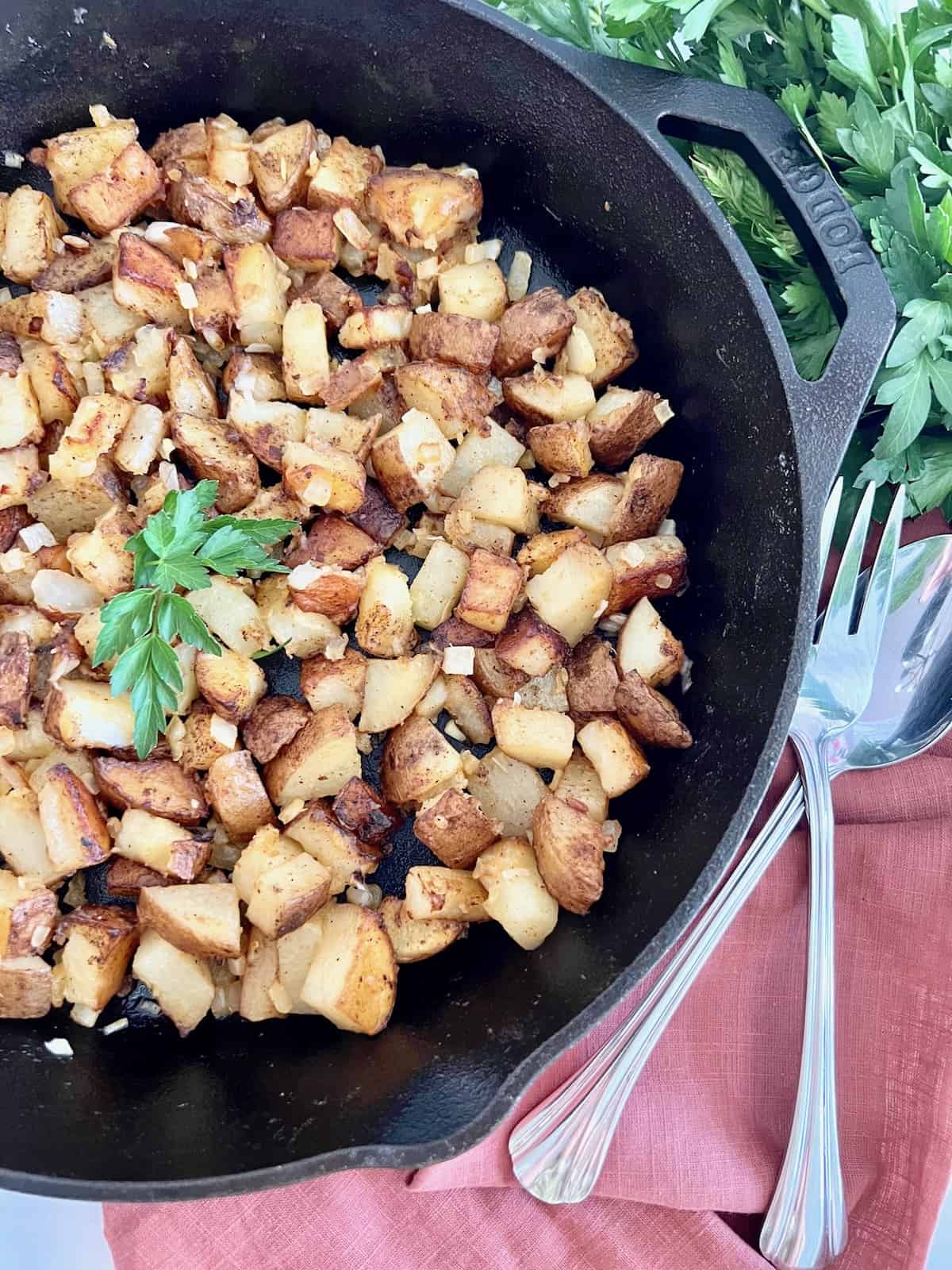 Pan Fried Potatoes & Onions Overhead closeup skillet parsley serving utensils and napkin