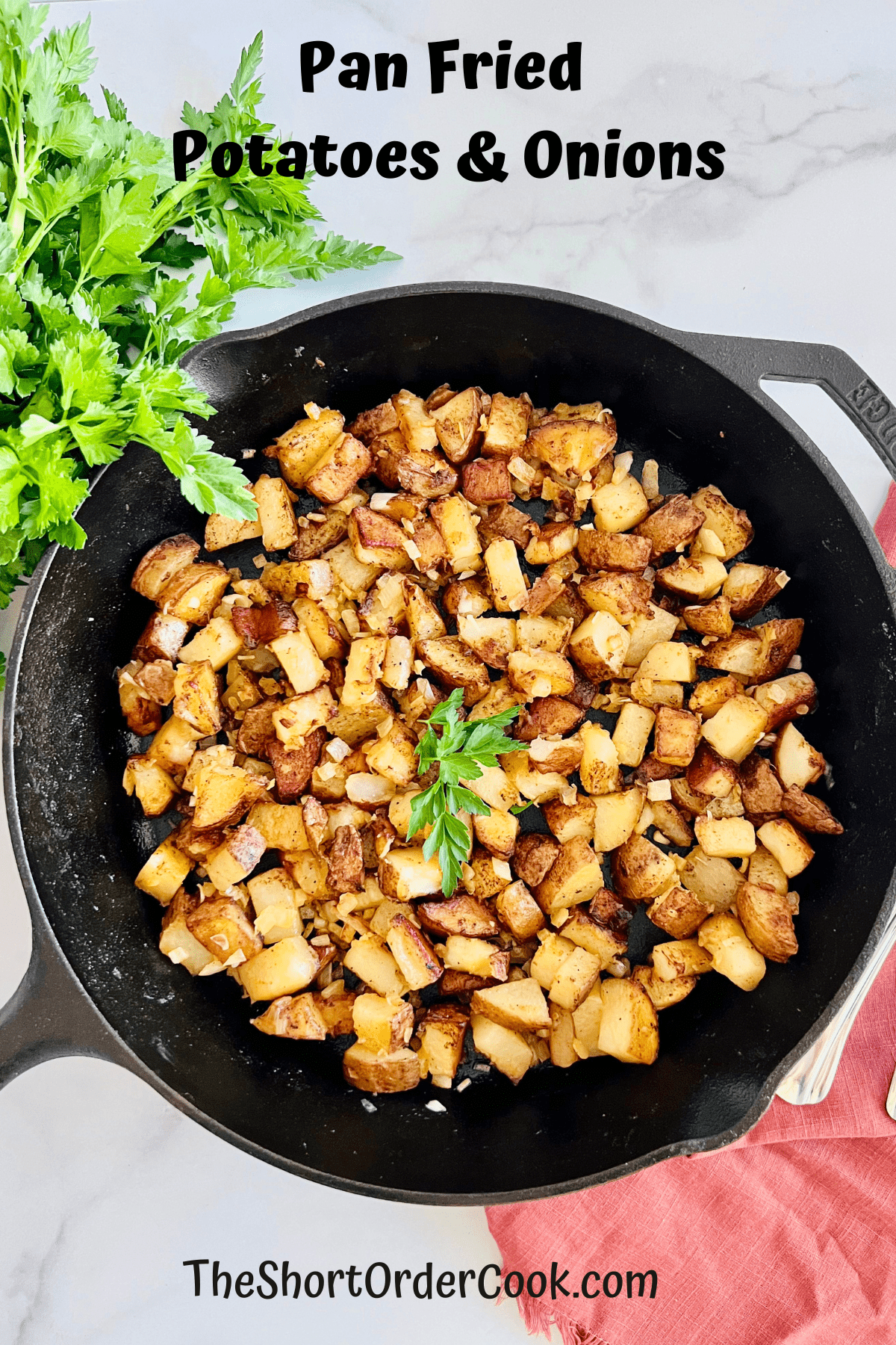 Pan Fried Potatoes & Onions in a skillet on the counter with fresh parsley and linen napkin.