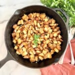 Potato cubes and onions fried in a skillet.