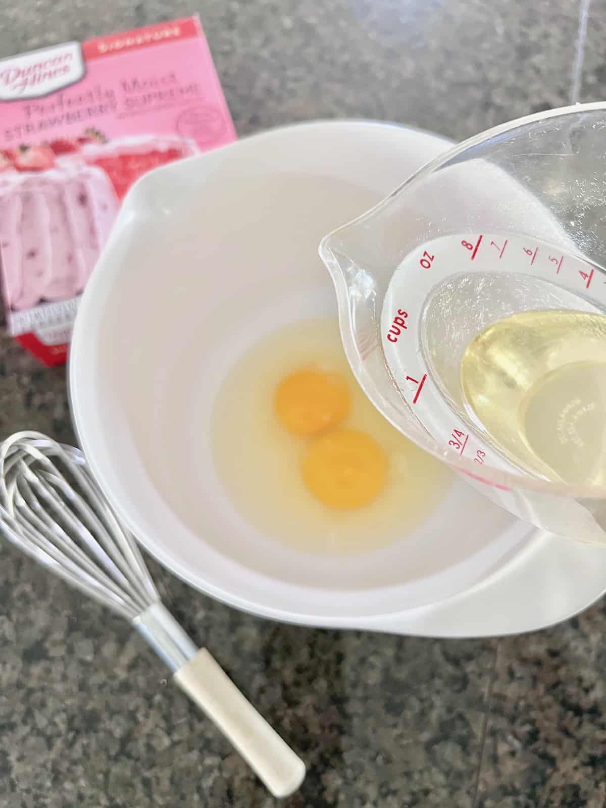 Eggs and oil to be whisked in a mixing bowl.