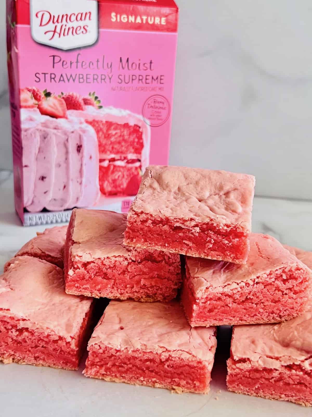 Strawberry Brownies stacked on the counter with box of duncan hines cake mix in the background.