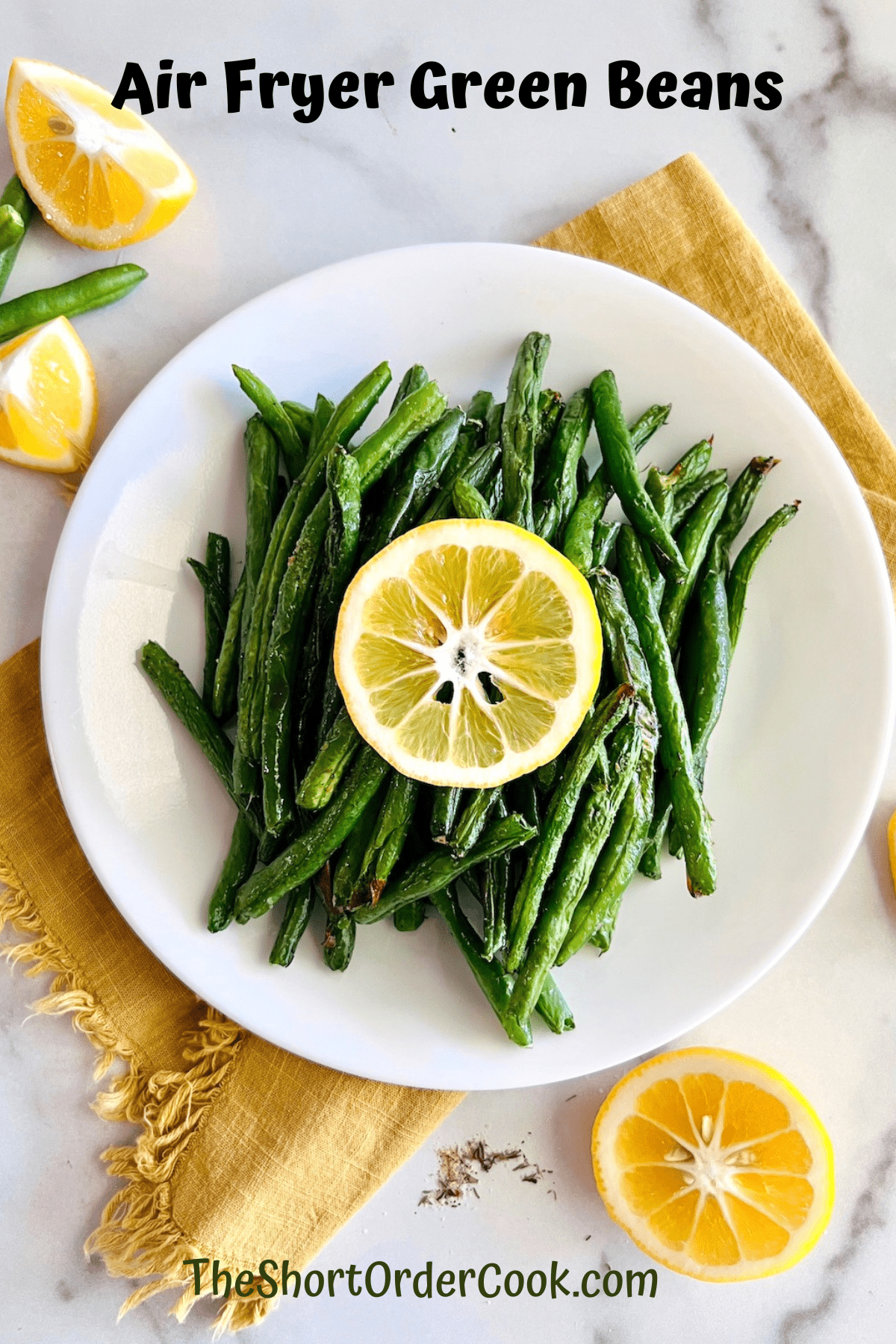 Air Fryer Green Beans on a white plate & topped with a slice of lemon.