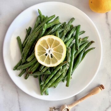 Air Fryer green beans plated with fresh lemon.