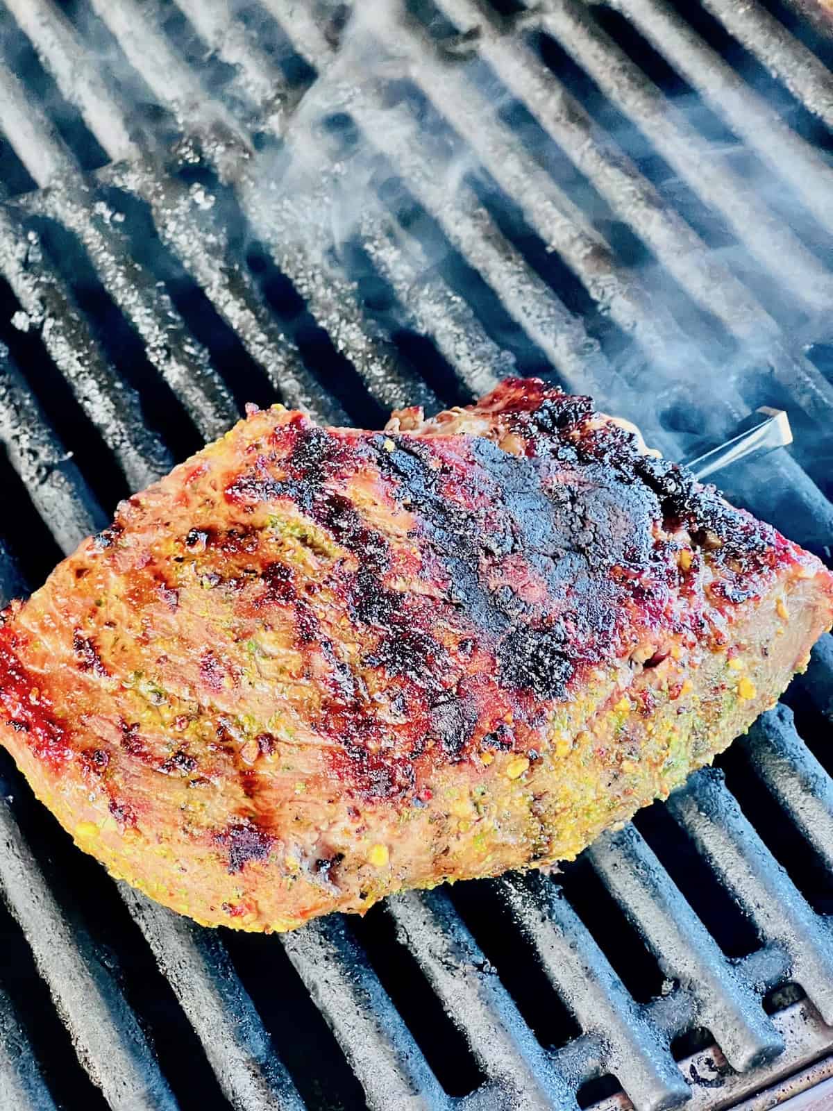 Tri-Tip On the grates of a gas grill with a dark crust & grill marks.