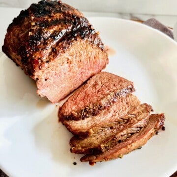 Grilled Tri-tip roast sliced and medium-cooked beef on a plate.