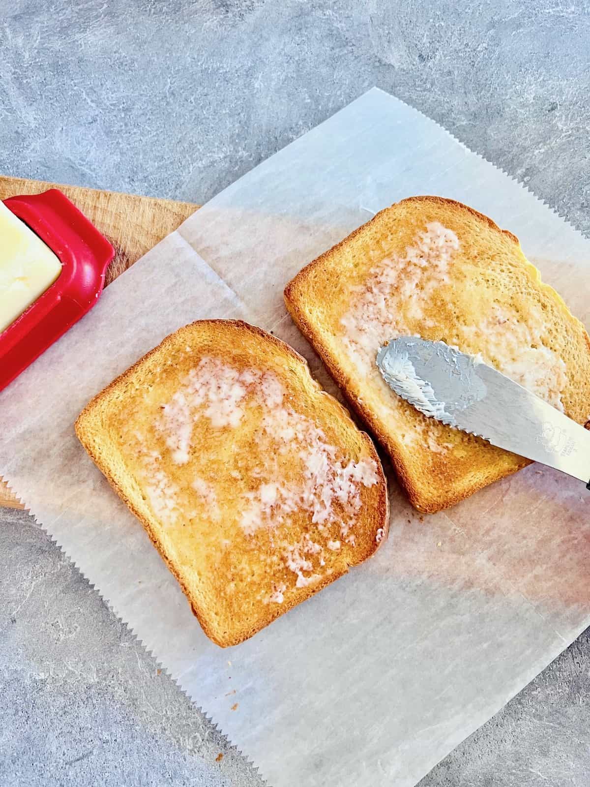 Buttering the toasted bread.