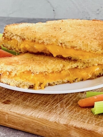 Microwave Grilled Cheese on a plate with cheddar melting out the slices.