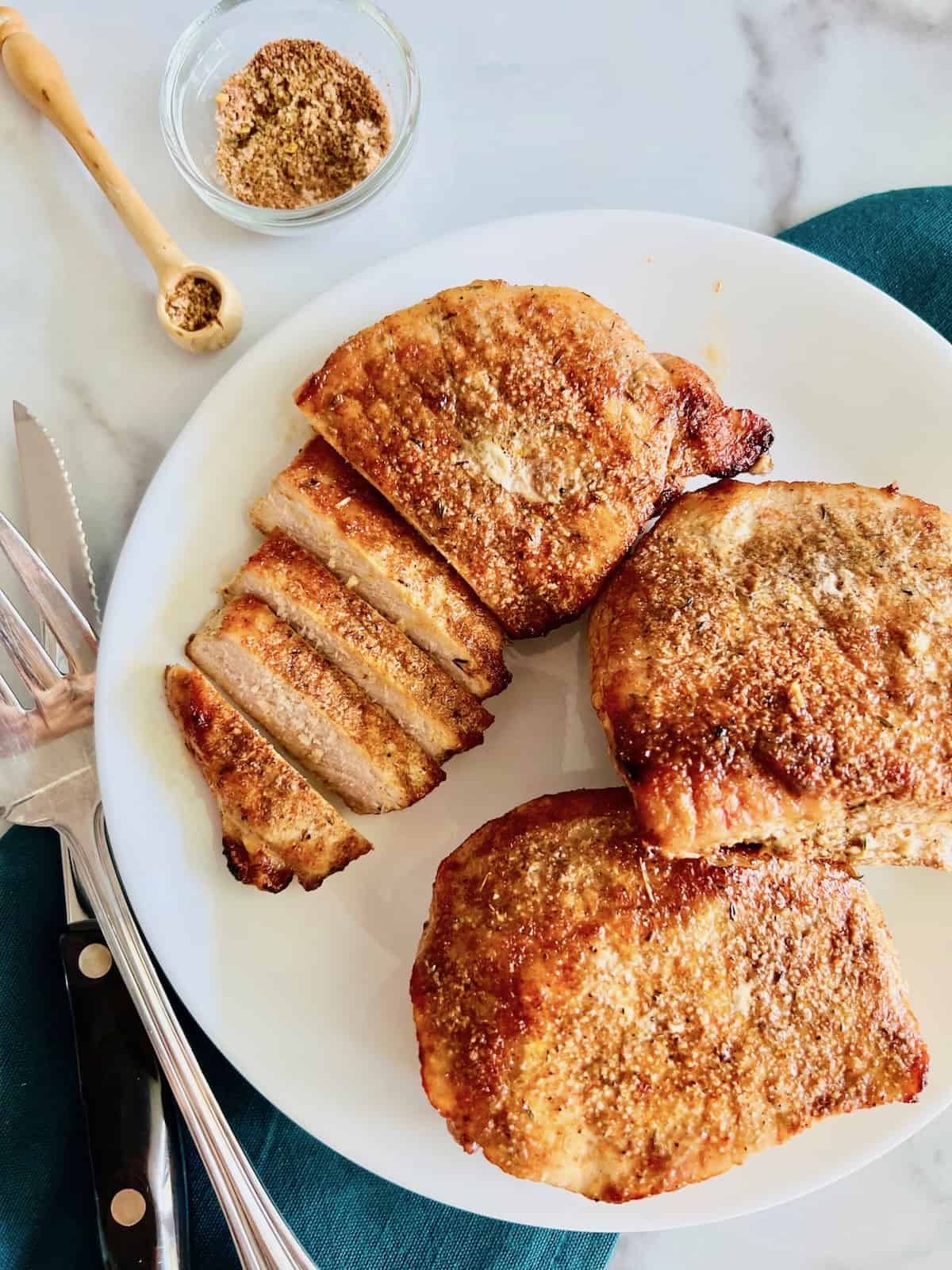 Air Fryer Pork Chops (no breading) Overhead plated and sliced with knife and serving fork.