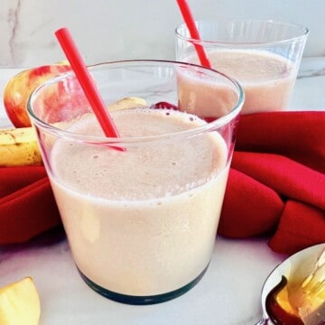 Apple Banana Smoothie poured into two glasses with red straws.