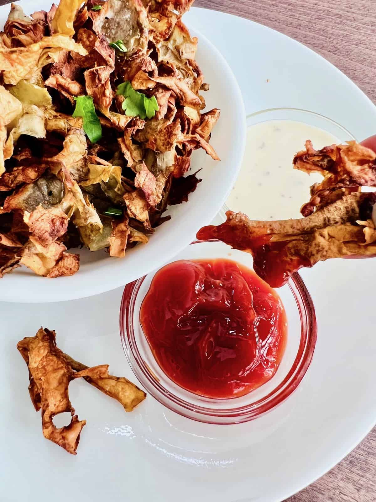 Crispy Air Fryer Potato Peels Dipping fried peels into ketchup.