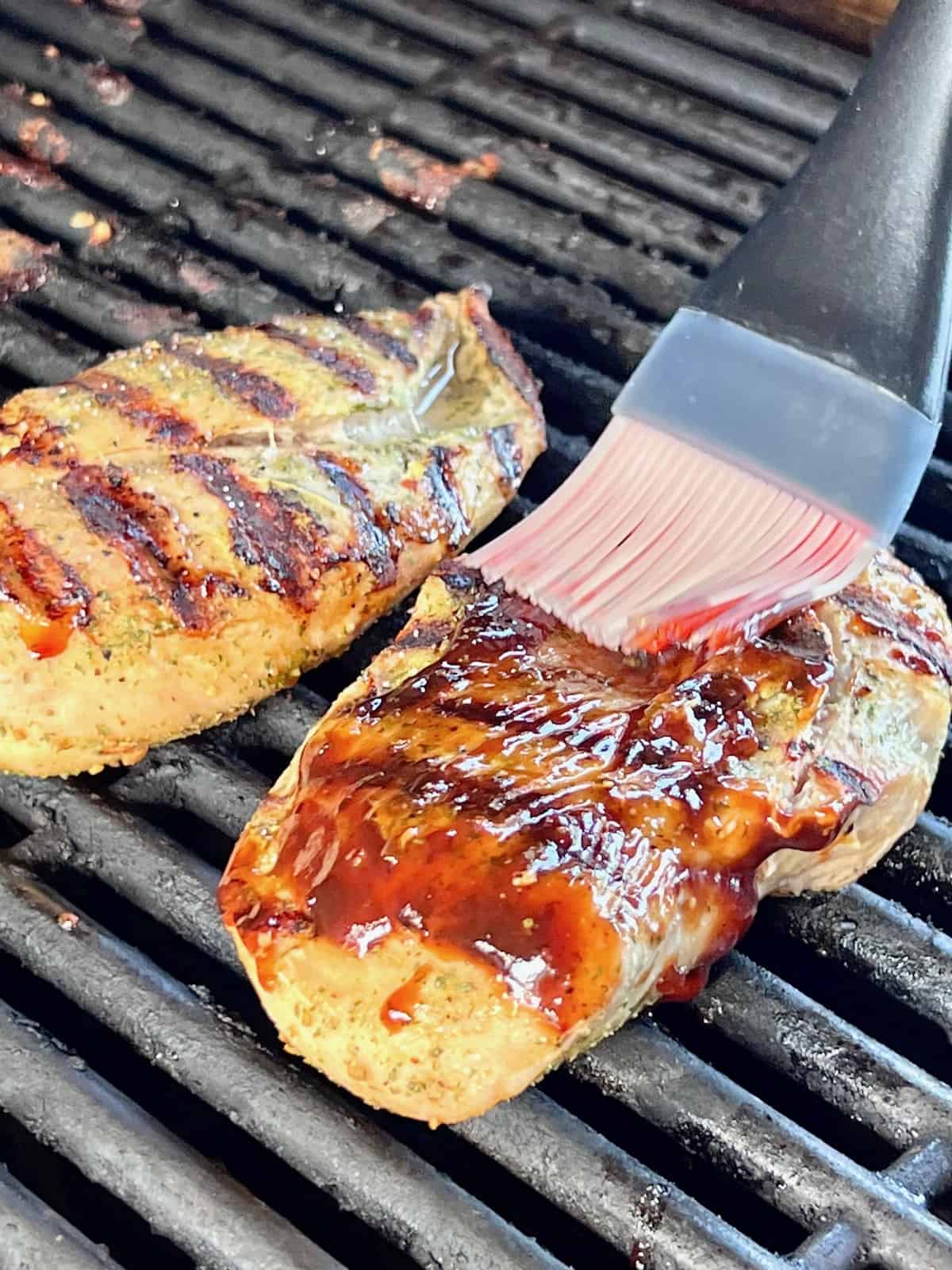 Grilled BBQ Chicken Breasts Basting with bbq sauce while on the grill.