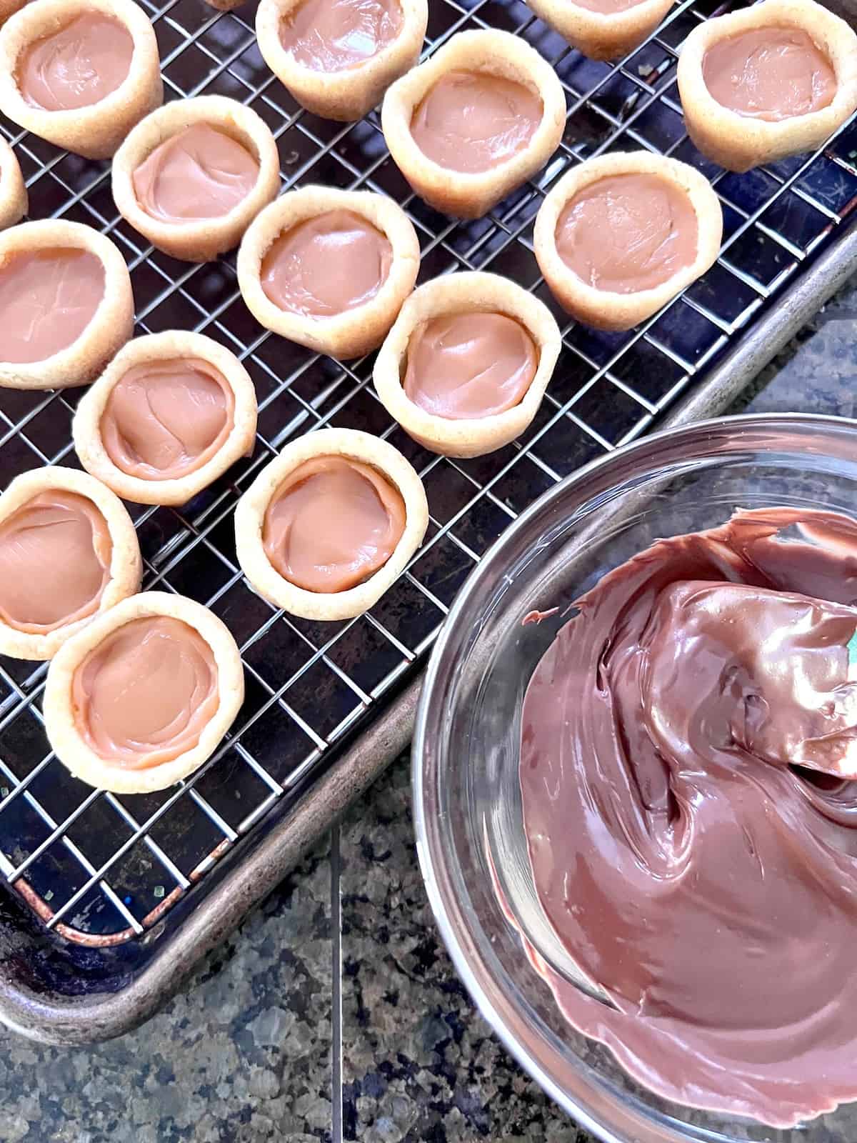 Sugar cookie cups filled with caramel next to bowl of melted chocolate.