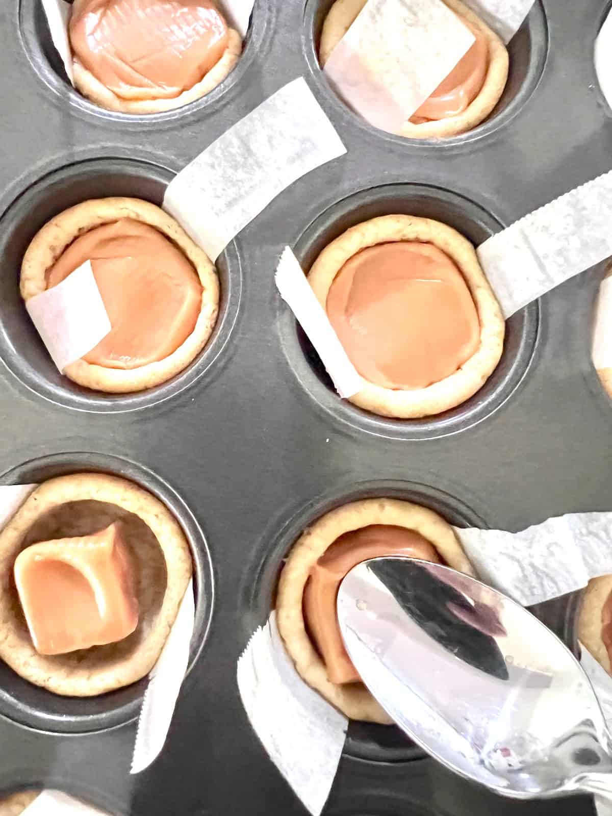 Twix Cookie Cups Using a spoon to press and smooth the soft caramel in the cookie cup