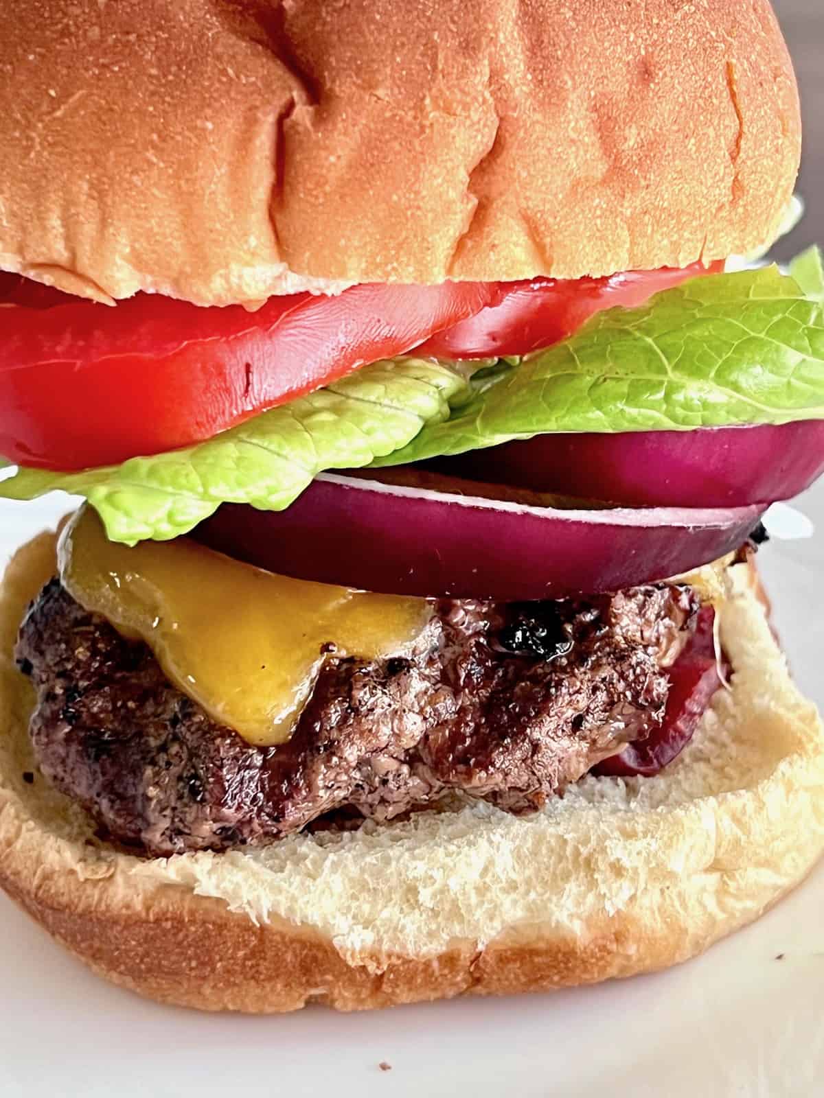 Wagyu Burgers Closeup of all the layers of toppings and a cheddar covered patty.