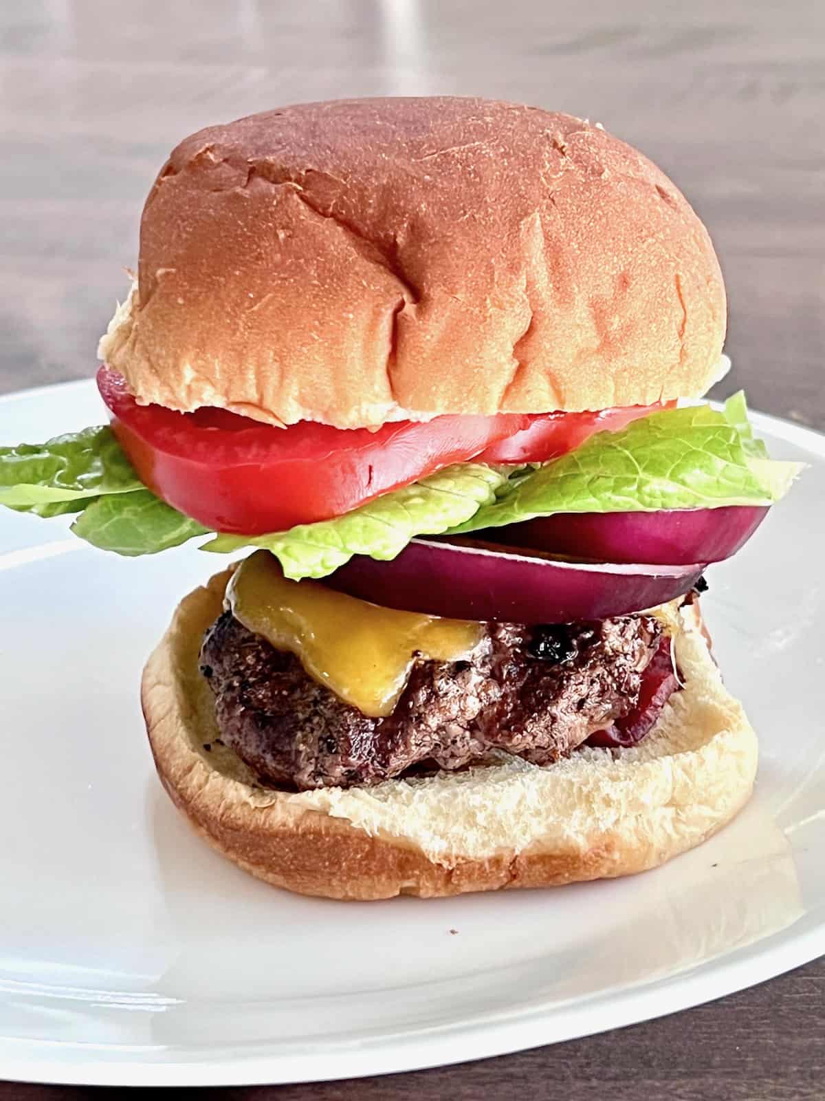 Wagyu Burgers Plated on a bun with lettuce tomato onion and cheese.