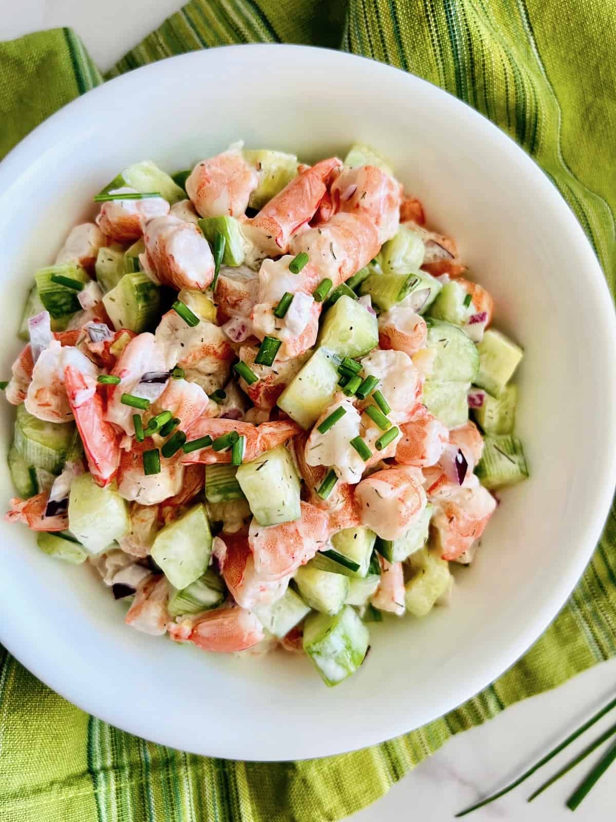 Cucumber Shrimp Salad In a bowl ready to eat with green linen napkin.