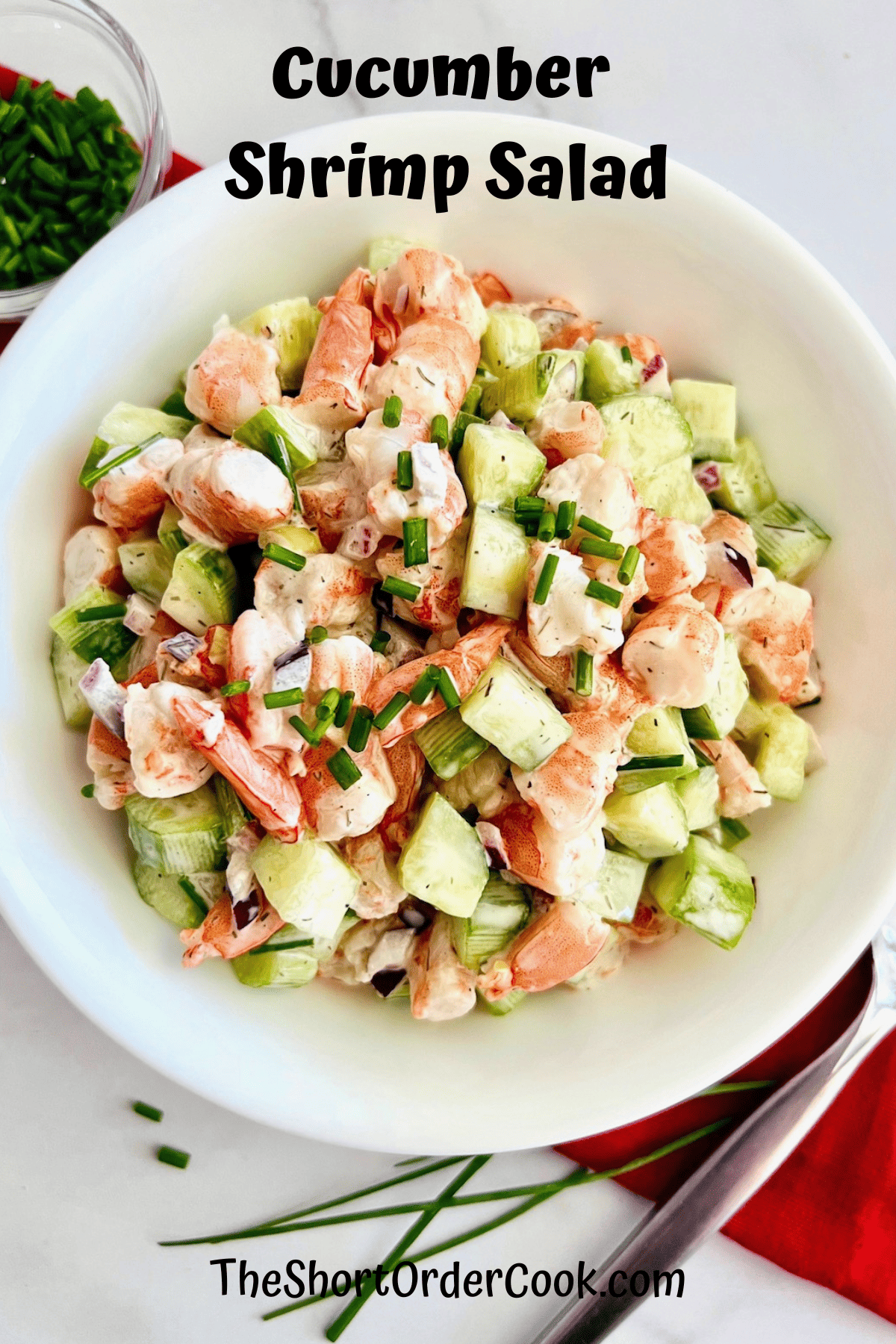 Seafood shrimp Salad with cucumber and onion in a serving bowl with fresh chives to the side.
