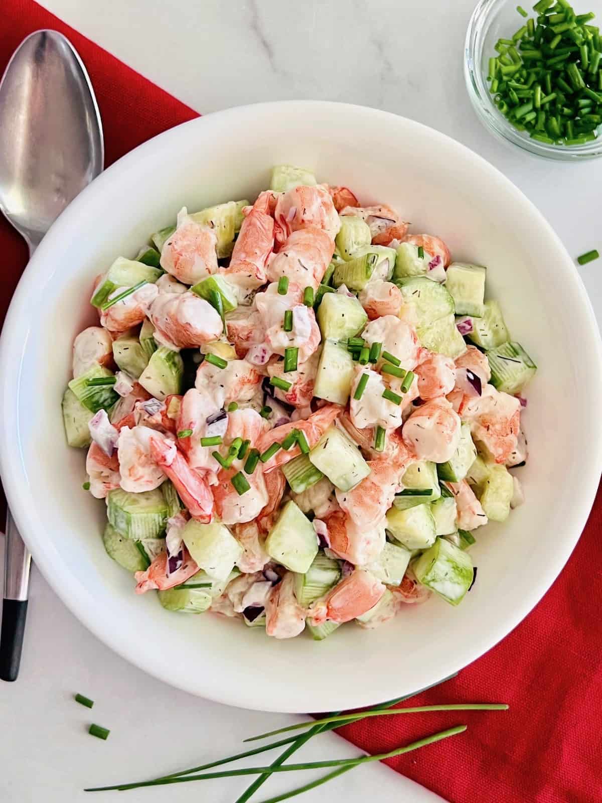 Cucumber Shrimp Salad with red napkin spoon and side bowl of fresh chives.
