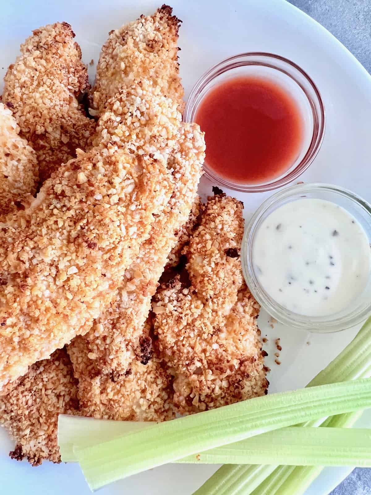 Breaded homemade chicken tenders coated in buffalo sauce before air frying. 
